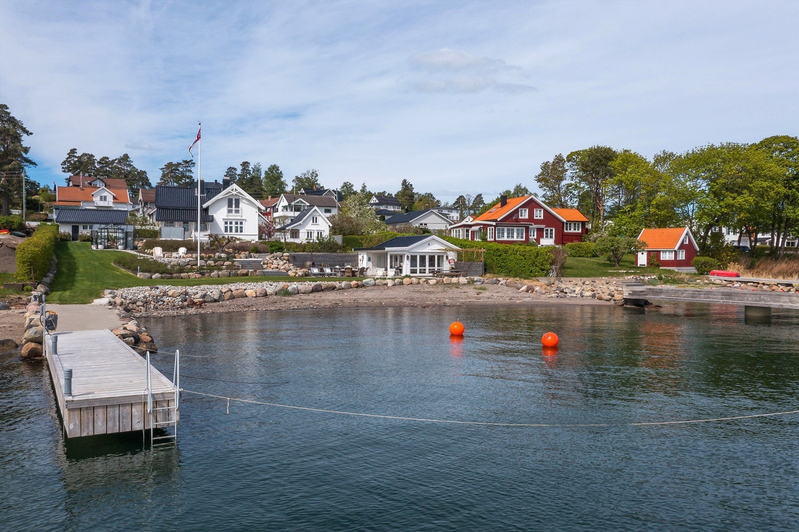 En velstelt og nydelig eiendom hvor hovedhus, dobbelt garasje, anneks og en sjøbod ligger omgitt av et vakkert hageanlegg med sandstrand og dypvannsbryggen med flere båtplasser på nedsiden. Galleribilde