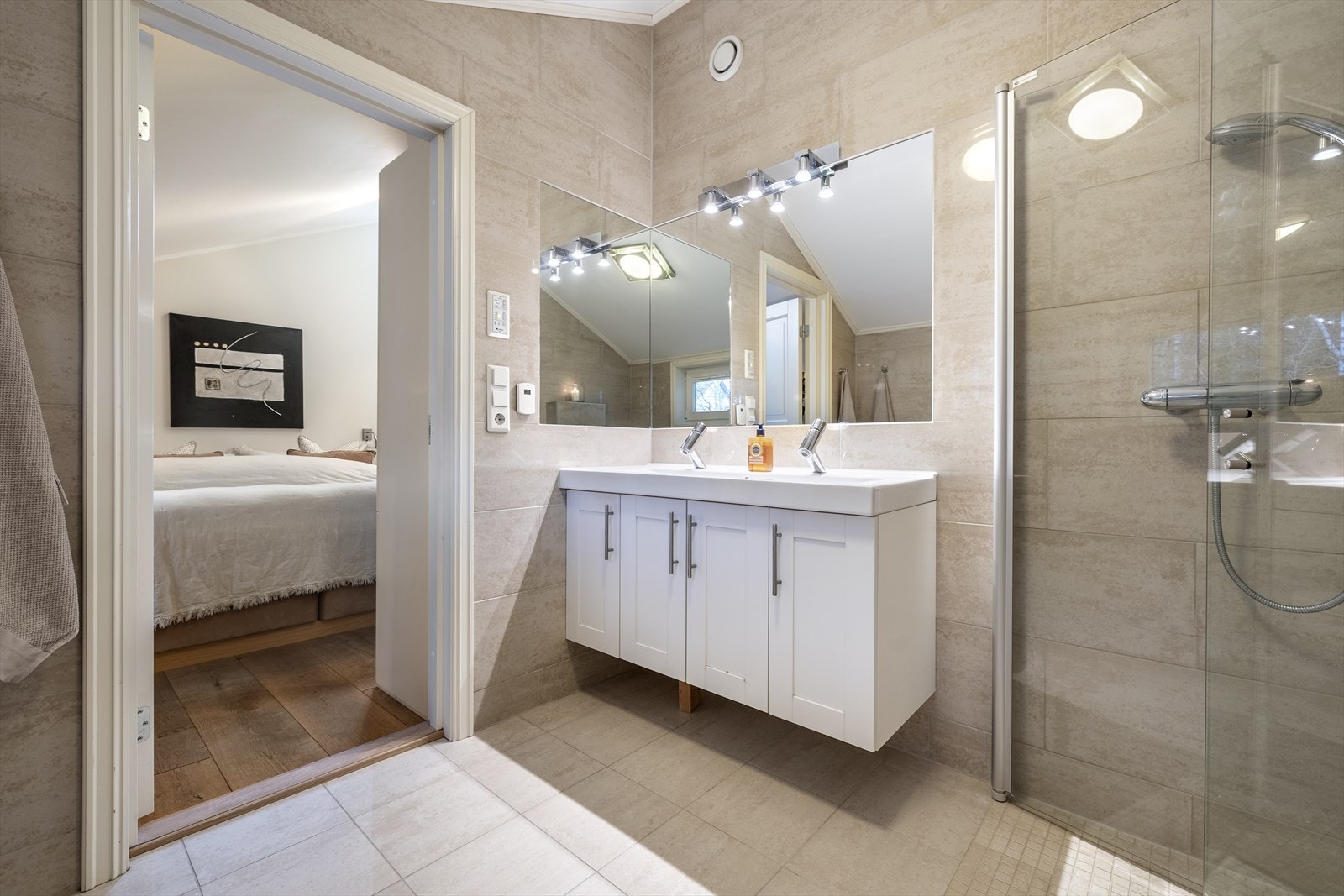 Badet er utstyrt med innfellbare glassdører, veggmontert toalett og bred baderomsinnredning med skap, dobbelservant, speil og belysning. Galleribilde