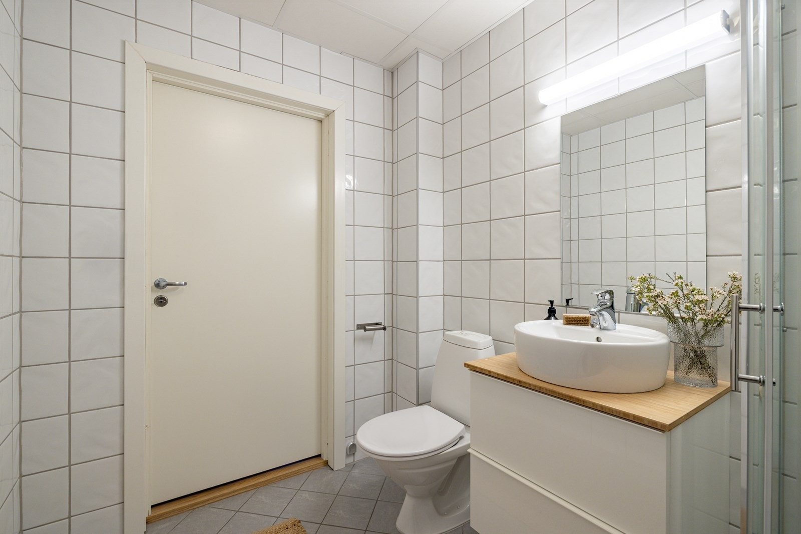 Servantskap med servant på topp, speil med lys over, og gulvstående klosett. Galleribilde