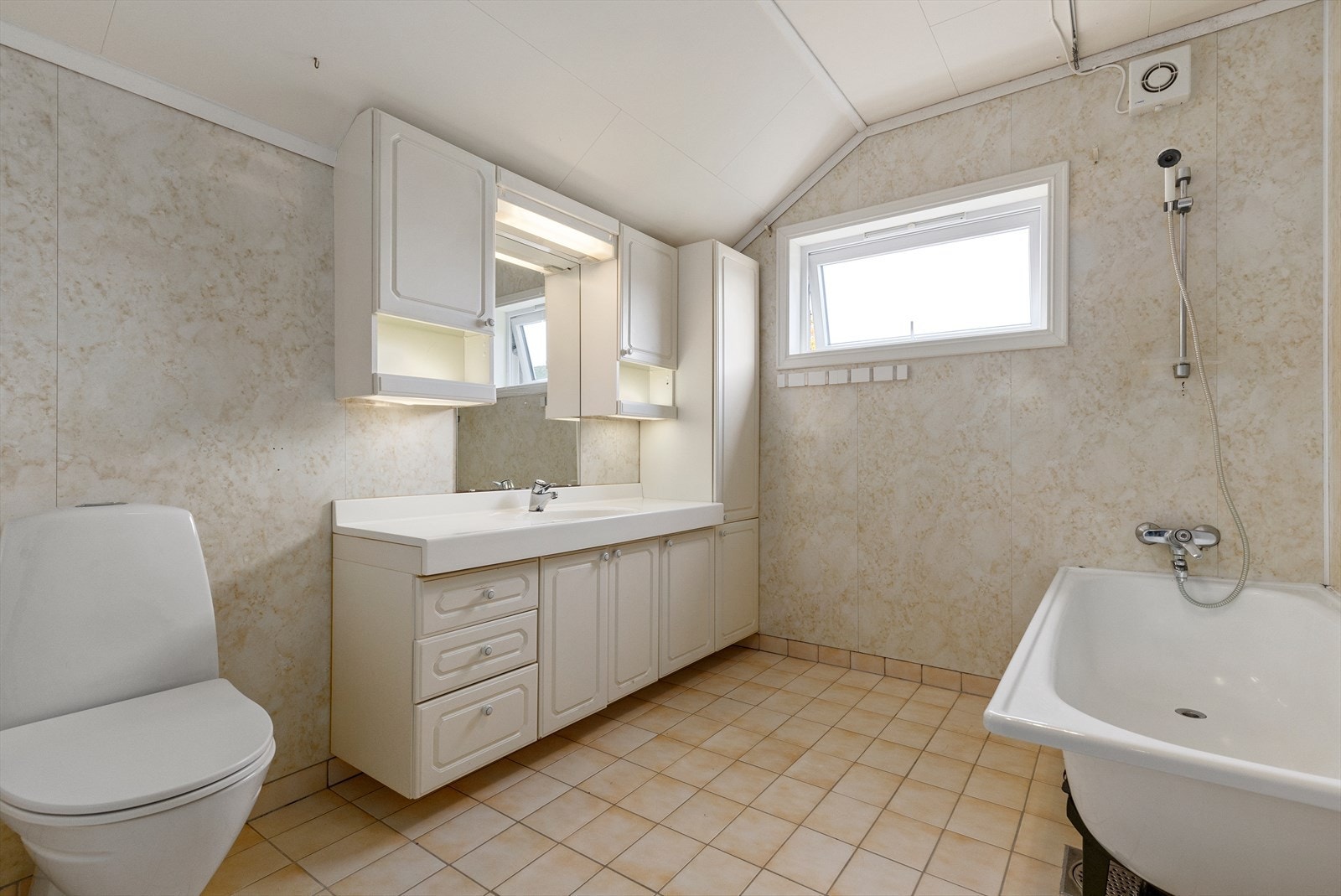 Bad i hovedetasjen har flislagt gulv med varmekabel og våtromsplater på vegg og er utstyrt med badekar, toalett og baderomsinnredning Galleribilde