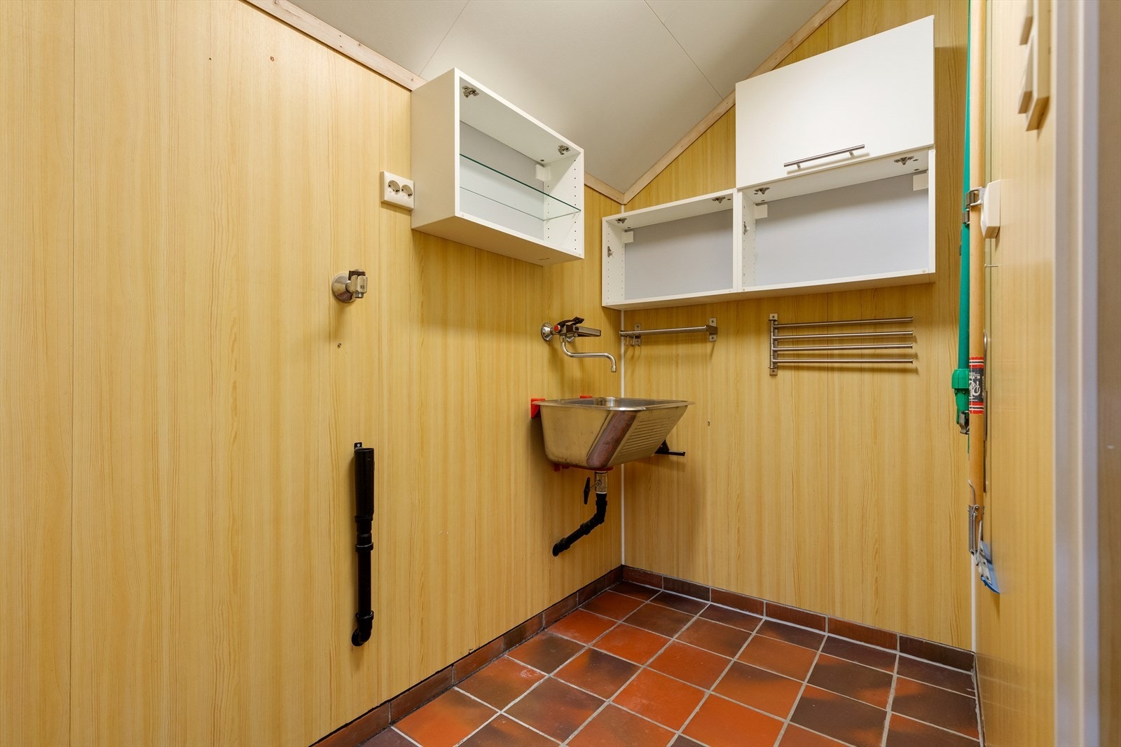 Vaskerom i hovedetasjen har flislagt gulv og våtromsplater på vegg | rommet er utstyrt med skyllekar og opplegg for vaskemaskin Galleribilde