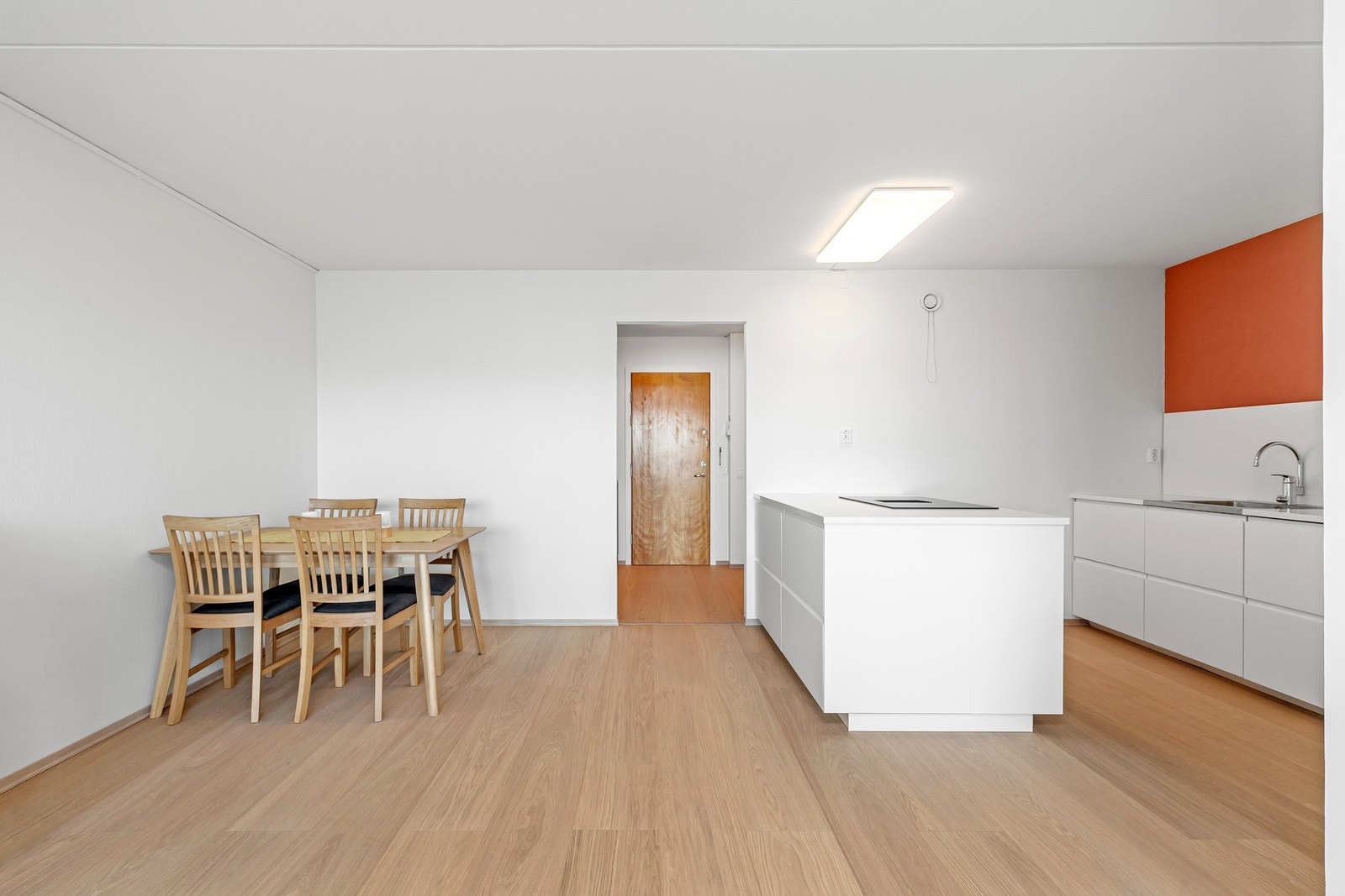Kjøkken og stue i en sosial og moderne, åpen løsning med kjøkkenhalvøy som et naturlig skille mellom sonene. Galleribilde