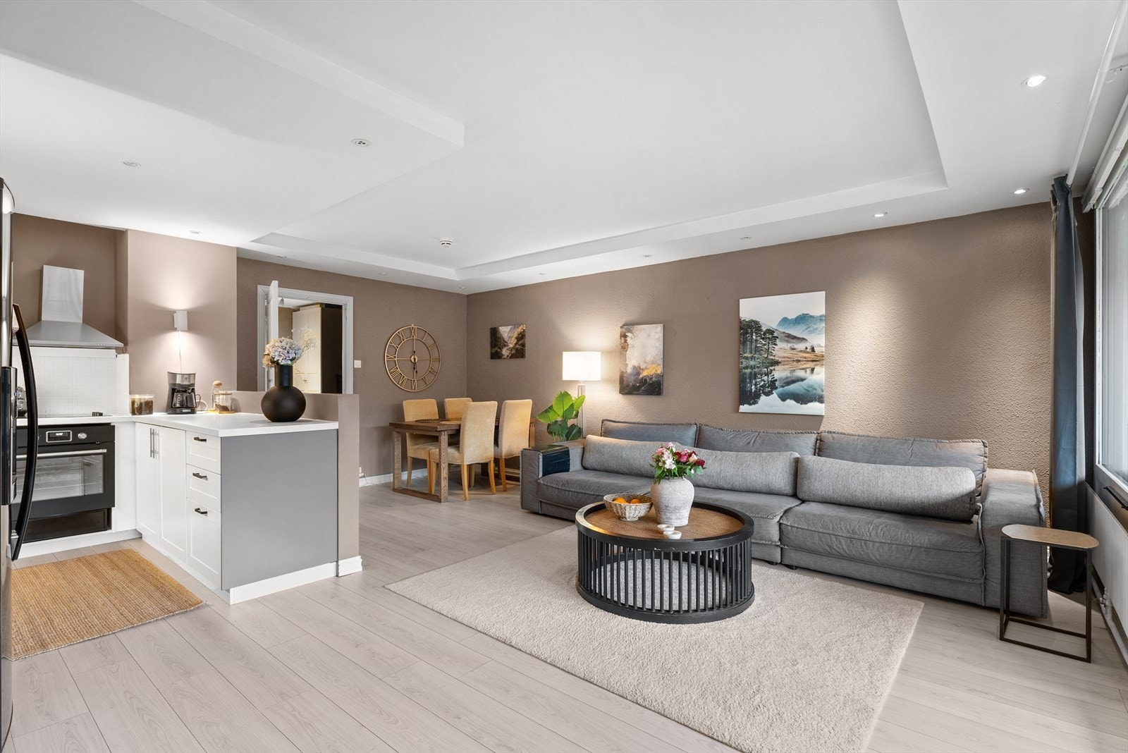 Kjøkkenet ligger tilbaketrukket innerst i rommet, med en liten halvvegg langs den ene siden mot stuen. Galleribilde