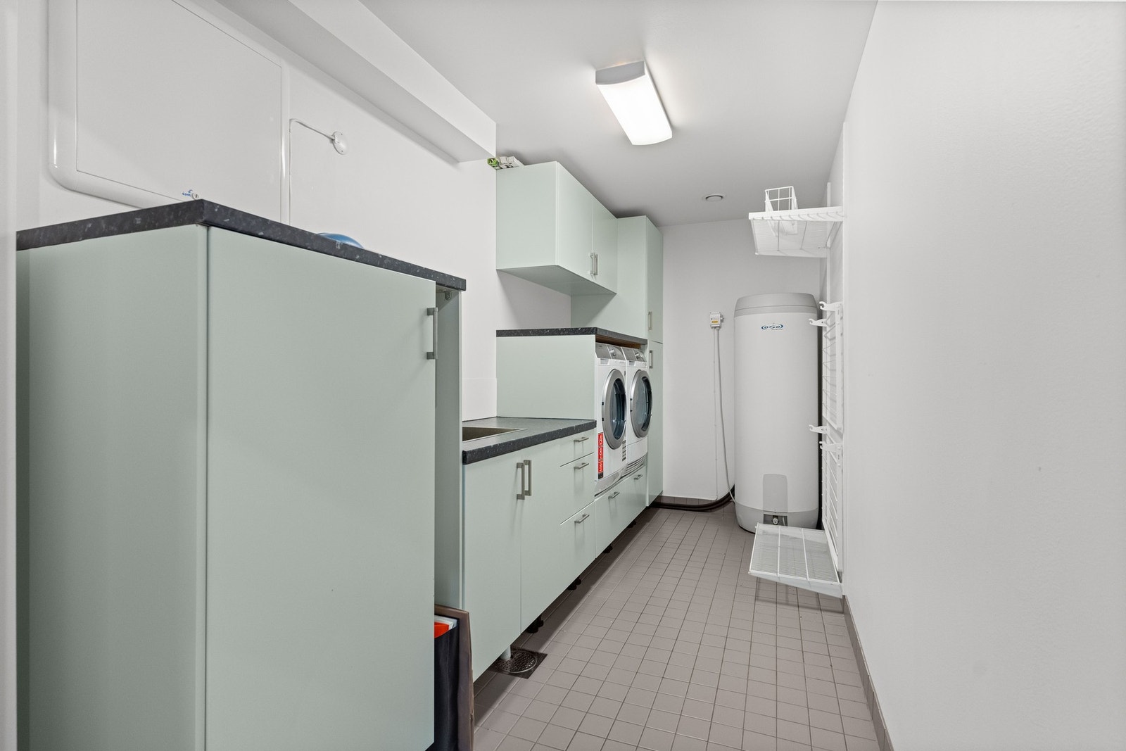 Vaskerommet har innredning med glatte fronter, benkeplater av laminat og nedsenket utslagsvask med ett-greps armatur. OSO varmtvannsbereder på 287 liter fra 2016. Her er det opplegg for vaskemaskin og tørketrommel. Galleribilde