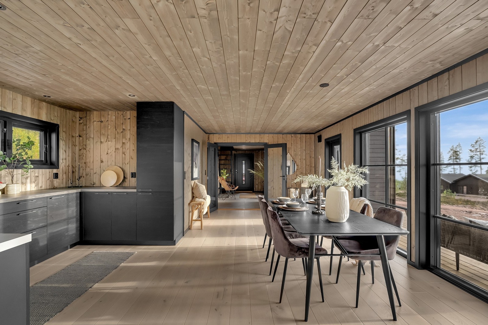 Kjøkkenet er fra Rotpunkt og har en moderne sort innredning som står i flott kontrast til treveggene og himlingen. Gulvet er dekket med eksklusive 22 cm brede eikegulv. Galleribilde
