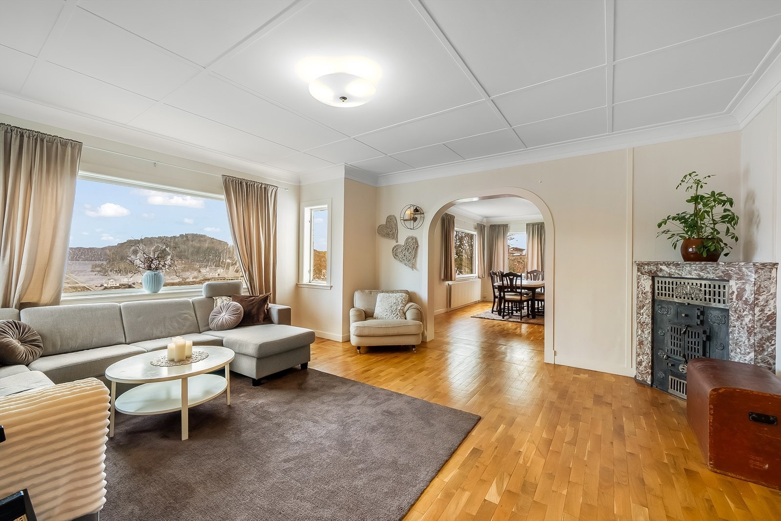 Gjennomgående stue med naturlig avdeling med bue mellom stue og spisestue. Eldre kamin i stua (ikke i bruk). Galleribilde