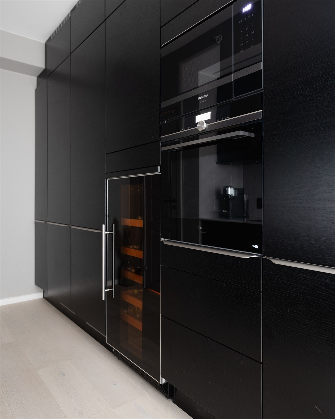 En vegg er dedikert til høyskap med rikelig oppbevaringsplass, integrert komfyr og mikro, vinskap samt kjøl. og fryseskap. Galleribilde