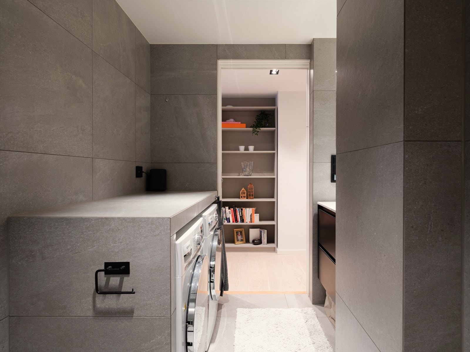 Når estetikk møter funksjonalitet - avsatt plass til vaskemaskin og tørketrommel, med flislagt arbeidsbenk på toppen for å ramme inn til et helhetlig møbel. Galleribilde