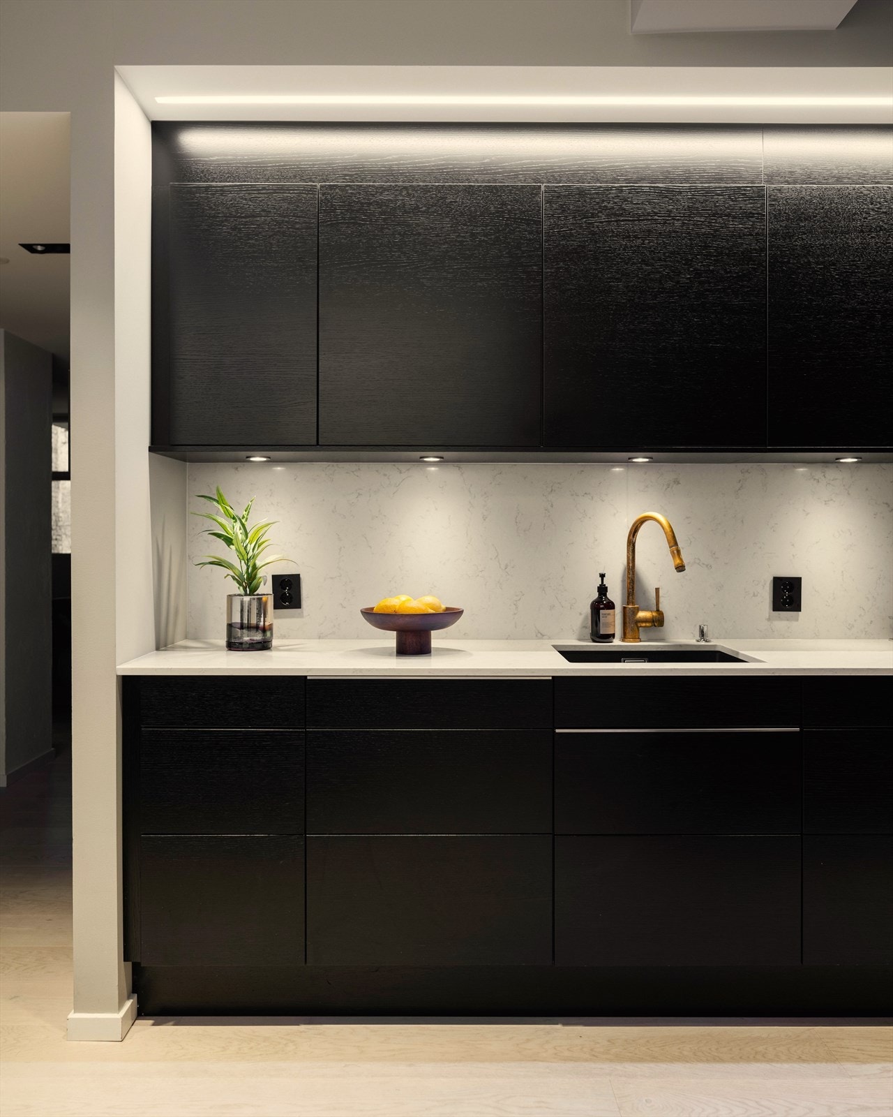 Kjøkkenet utgjør et stilrent møbel i seg selv, med integrert belysning som gir en lun og stemningsfull atmosfære på kveldstid. Galleribilde