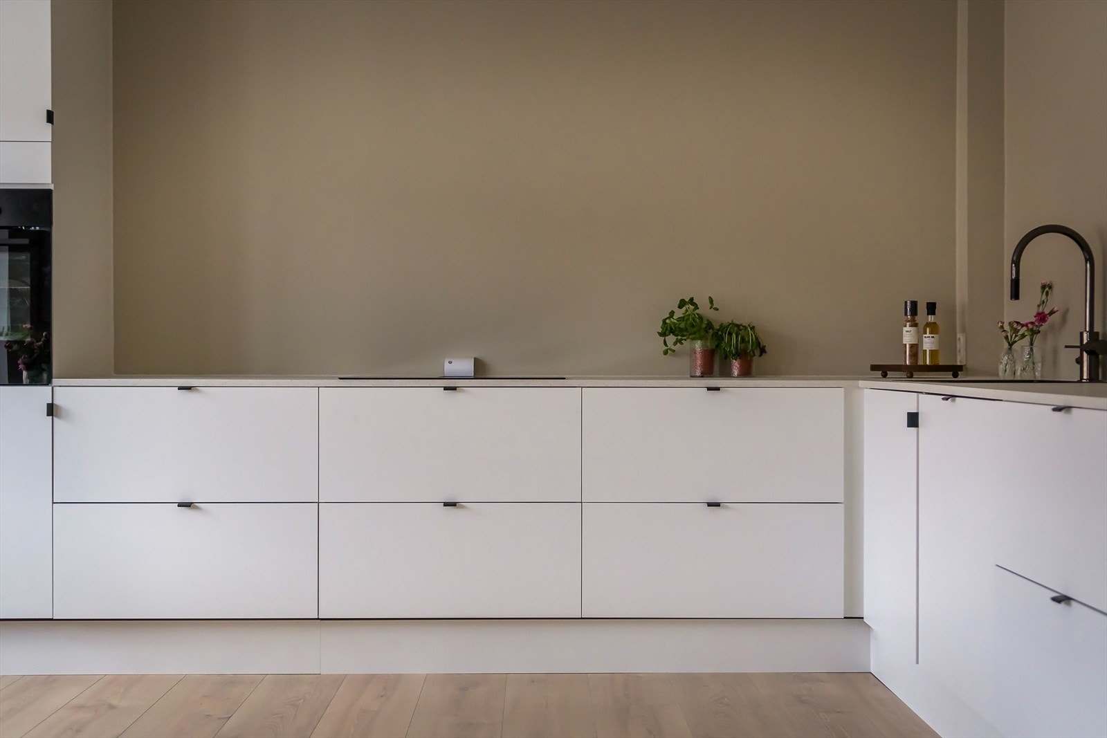 Lys kjøkkeninnredning med glatte fronter og benkeplate av laminat Galleribilde