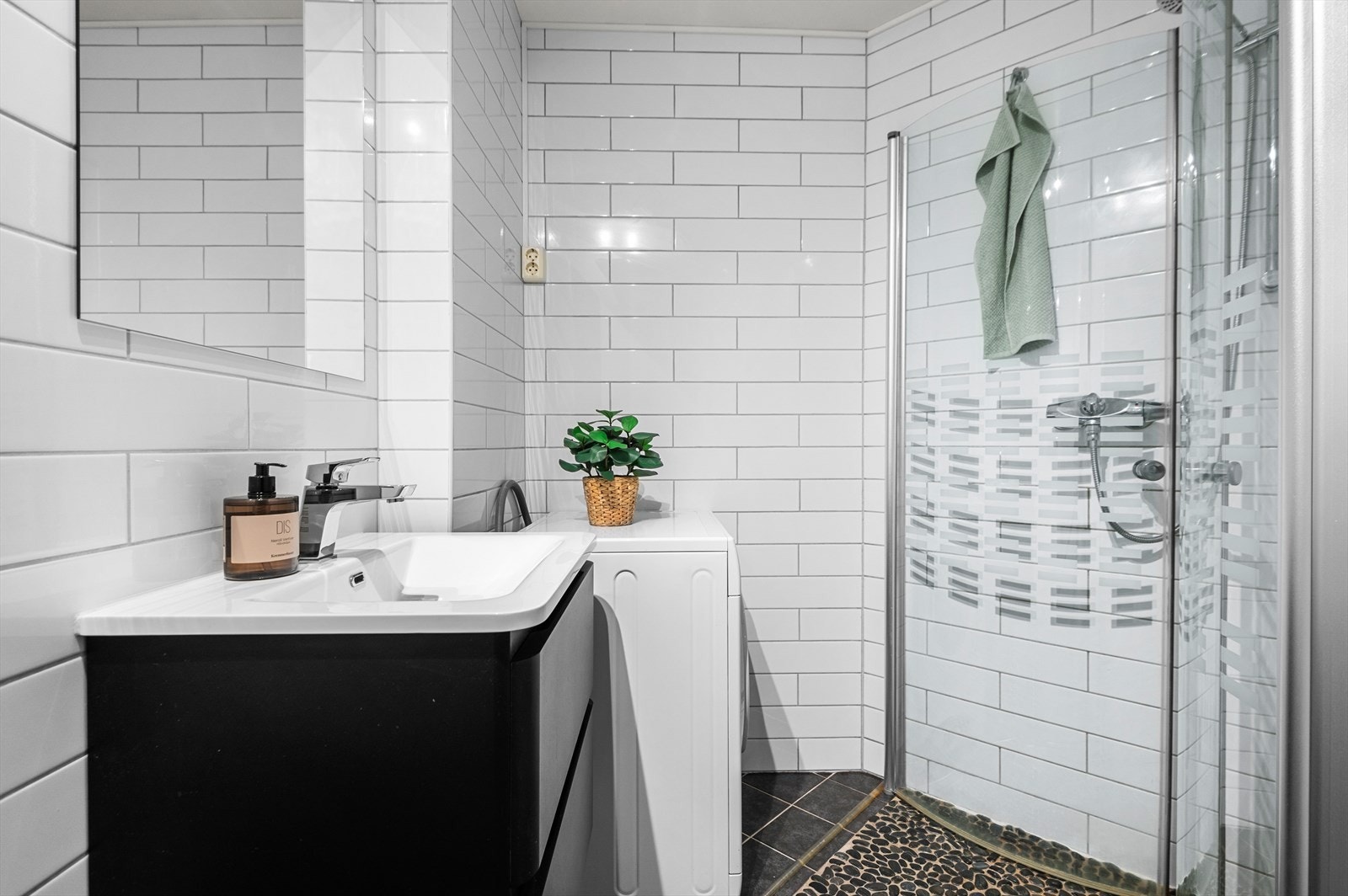 Badet er innredet med dusjhjørne med praktiske innfellbare dusjdører, opplegg for vaskemaskin, servant, servantskap og veggmontert wc. Galleribilde