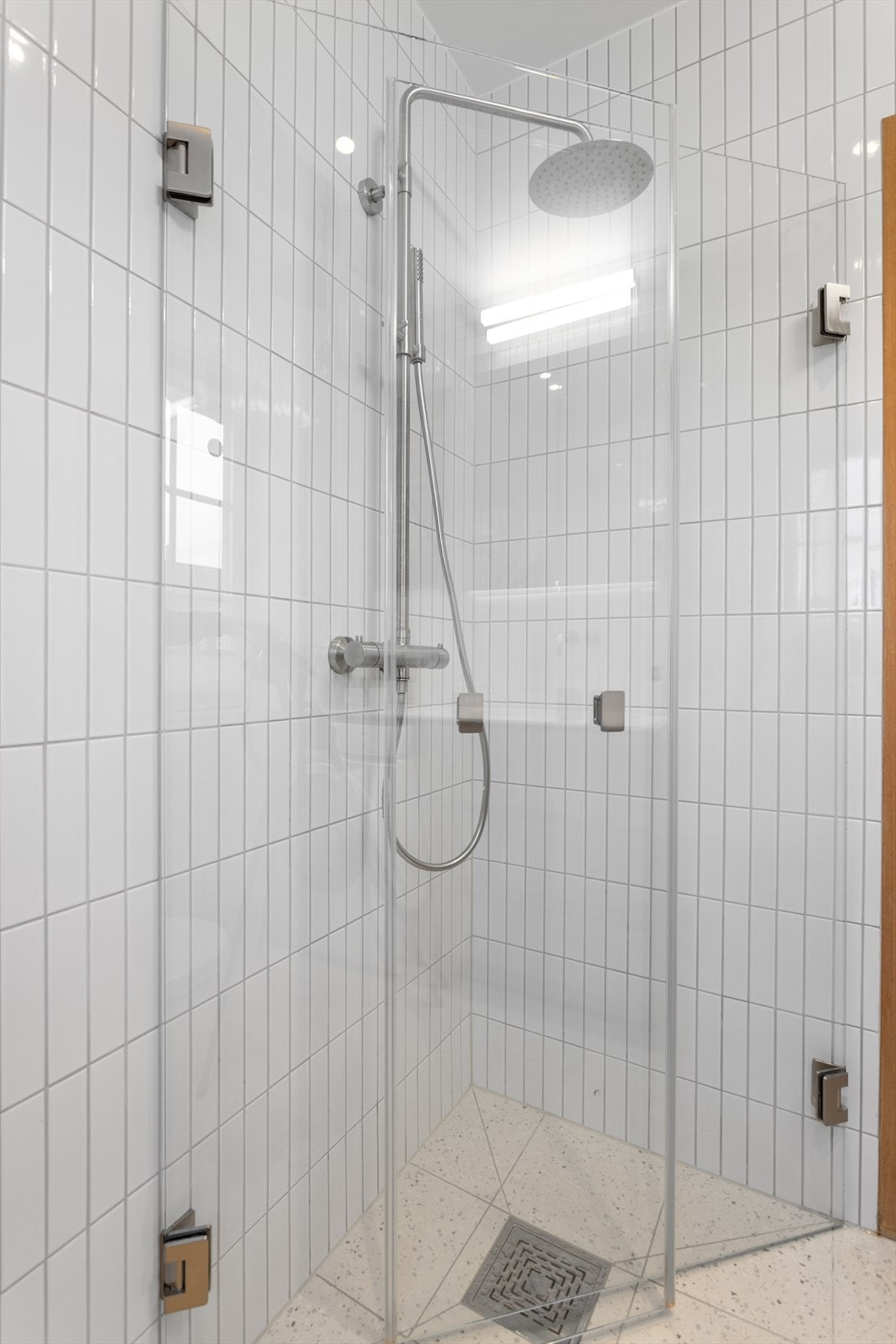 Badet består av vegghengt wc, heldekkende Corian servant med skuffer under og dusj i hjørne med innadslående dører. Det er i tillegg opplegg for vaskemaskin. Galleribilde