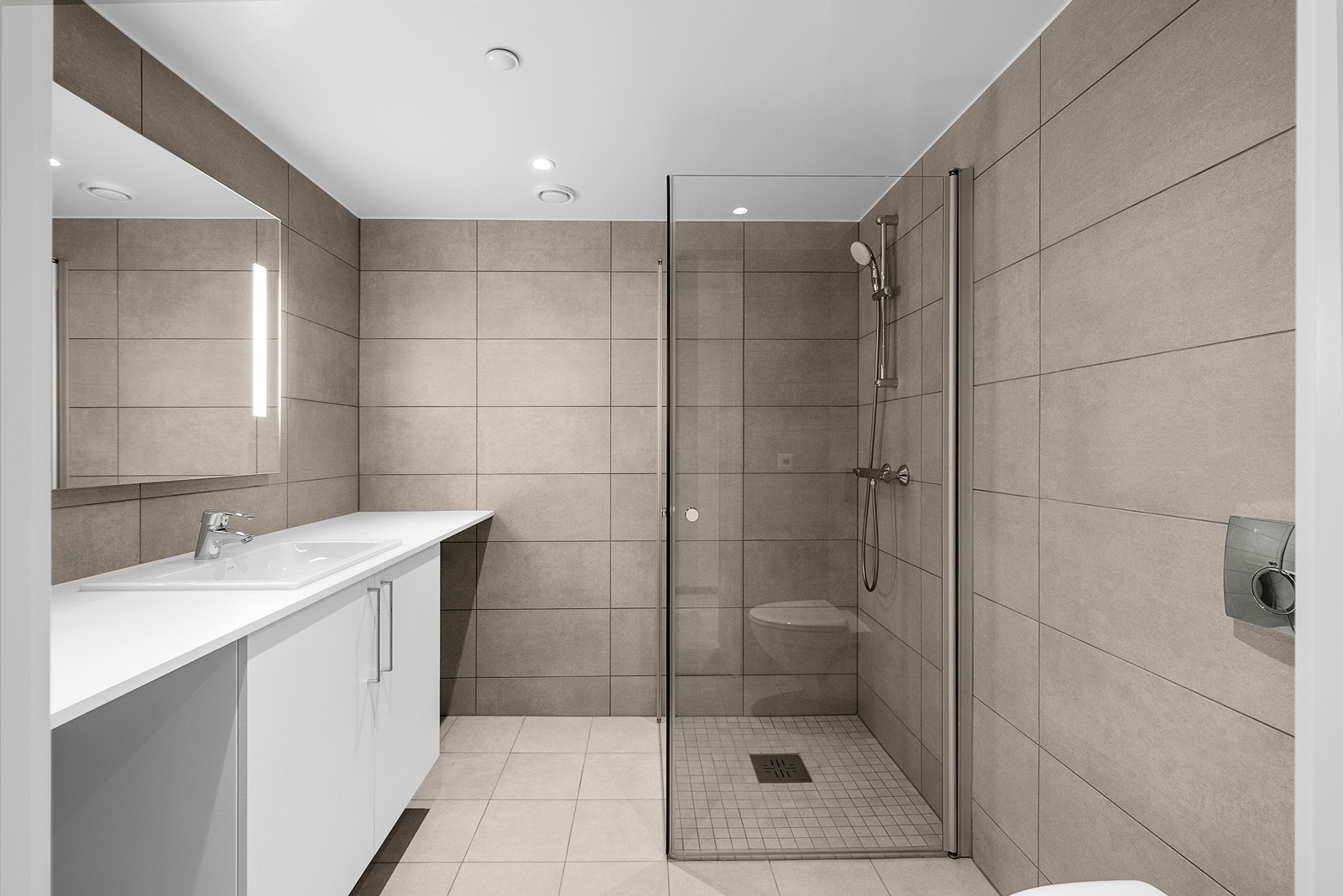 Romslig flislagt bad med downlights fra himling Galleribilde