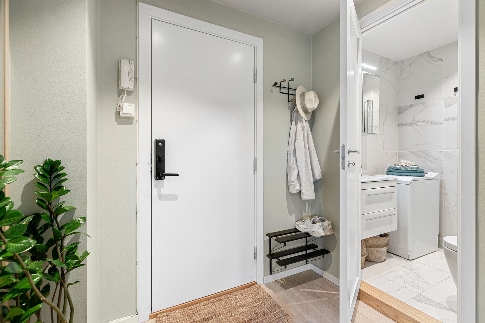 Innbydende entré som gir et lyst og positivt førsteinntrykk av boligen. Her er det plass til oppheng av yttertøy, og porttelefonen er praktisk plassert Galleribilde