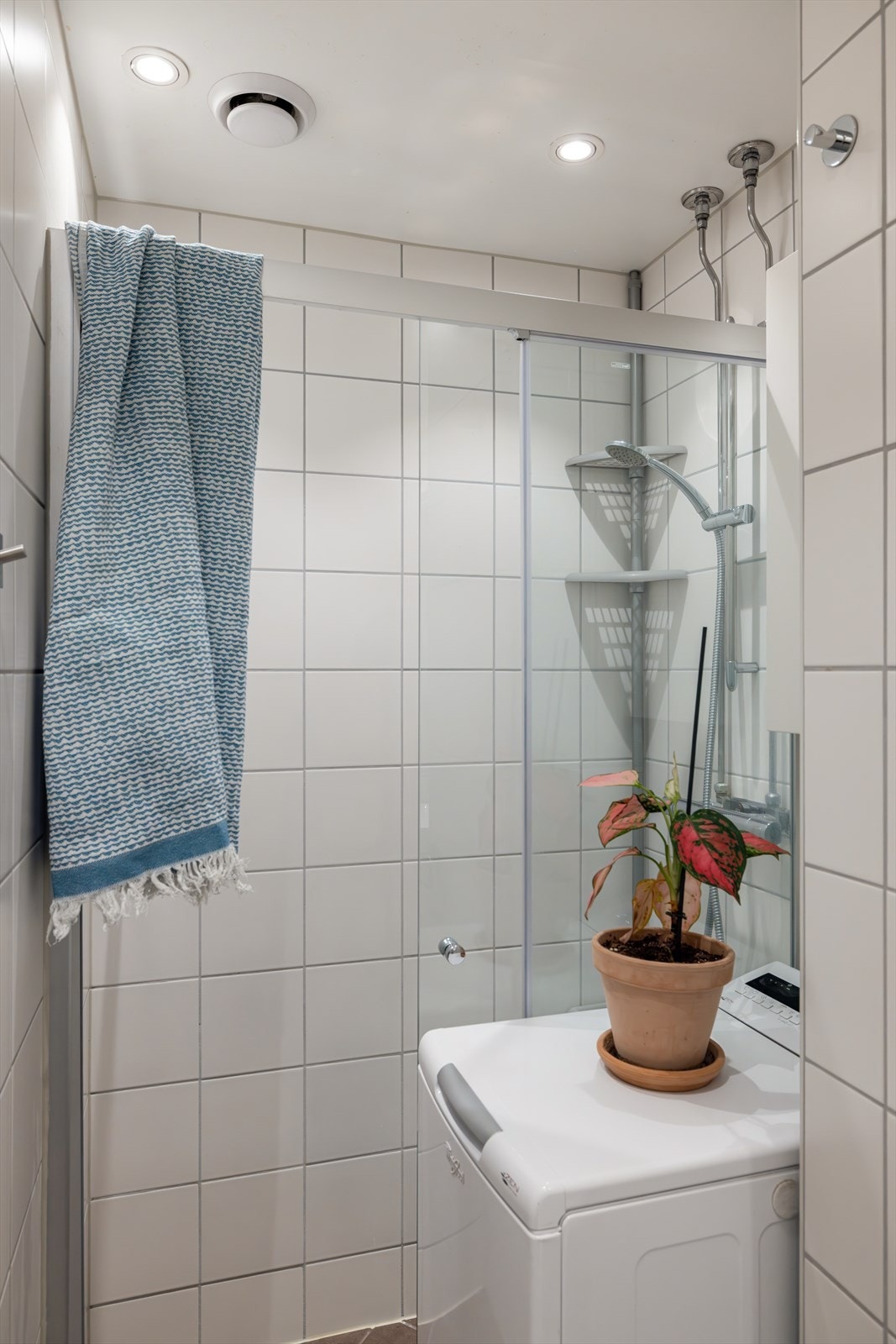 Badet er pent innredet med vegghengt toalett, vaskemaskin, dusjhjørne med dusjdører og servant med tilhørende skap og speil. Galleribilde