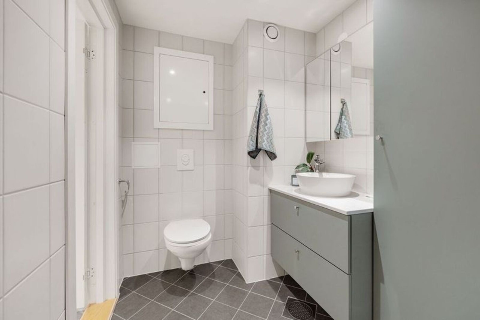 Badet er innredet med vegghengt toalett, samt moderne baderomsinnredning med speil Galleribilde