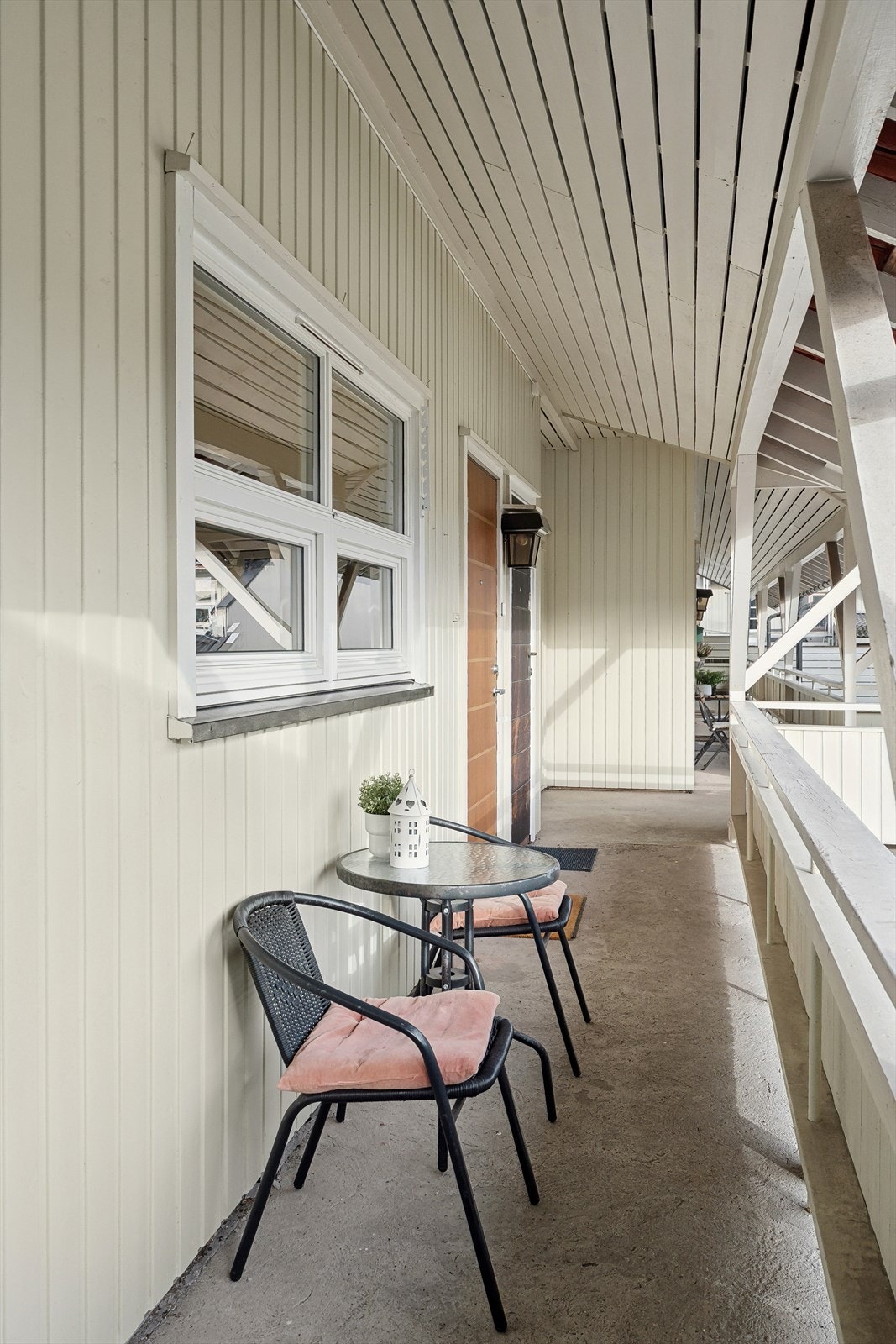 Leiligheten har et hyggelig inngangsparti via felles atrium/svalegang med plass til cafèsett. Galleribilde