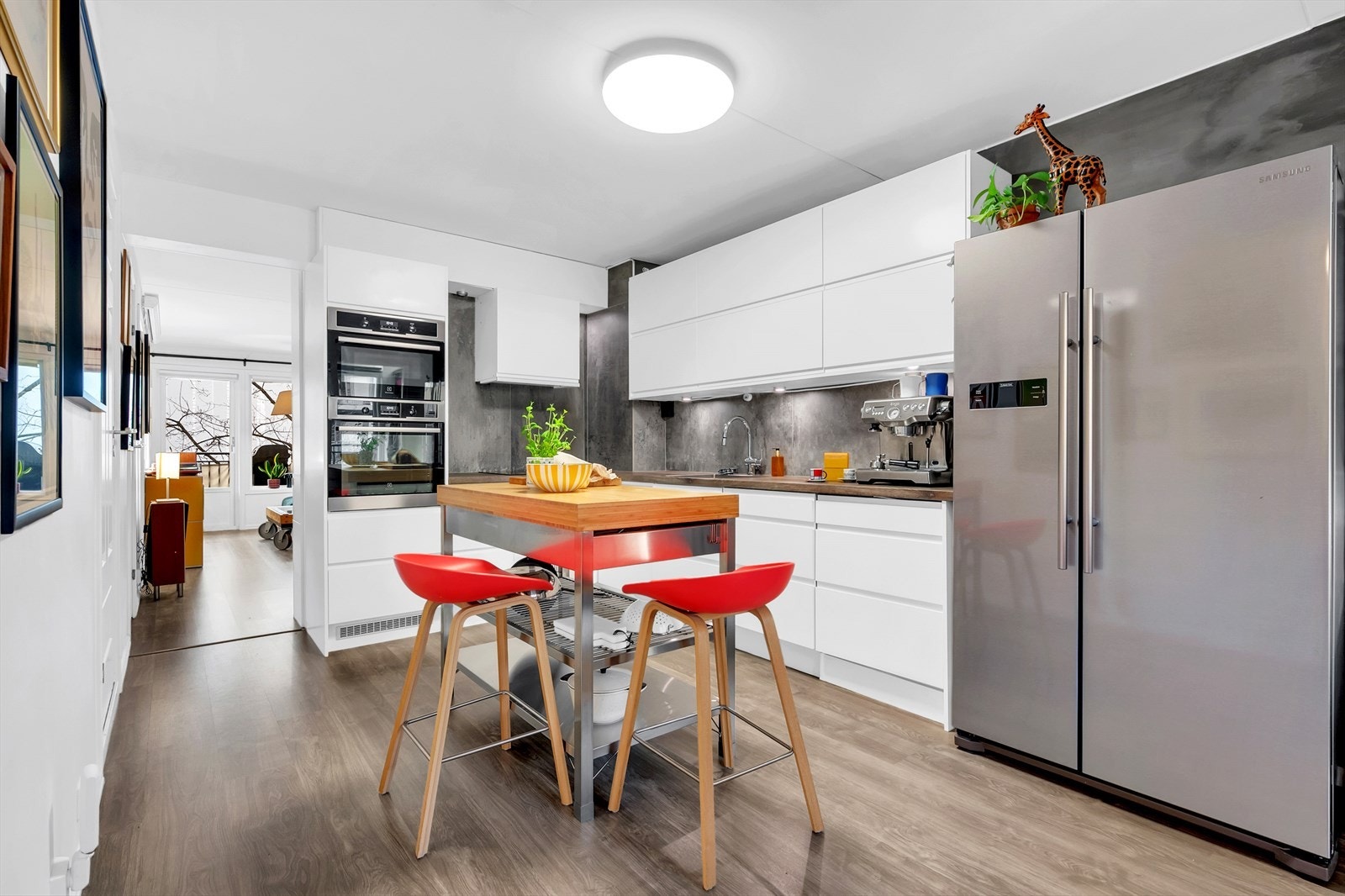 Kjøkkenet har glatte fronter, laminatbenkeplate med nedfelt vaskekum, samt fliser og belysning over benkeplaten. Galleribilde