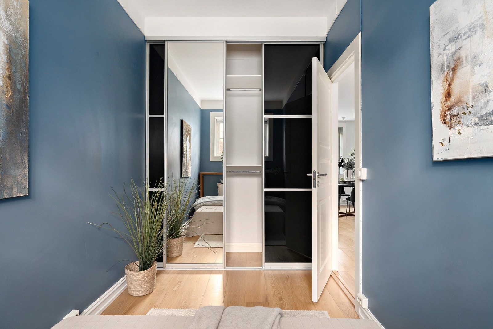 Den ene kortveggen er innredet med en stor skyvedørsgarderobe med speildører Galleribilde