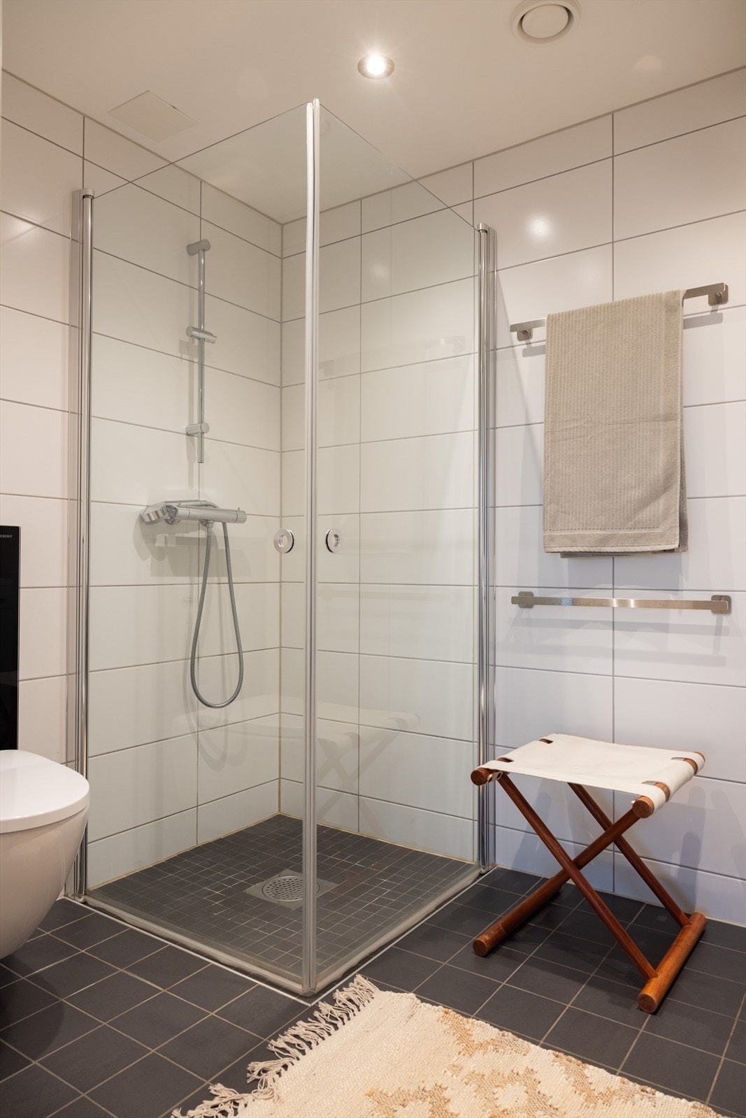 Badet er innredet med vegghengt klosett, servant med innredning, speil m/lys og dusjhjørne med svingbare foldedører. Galleribilde