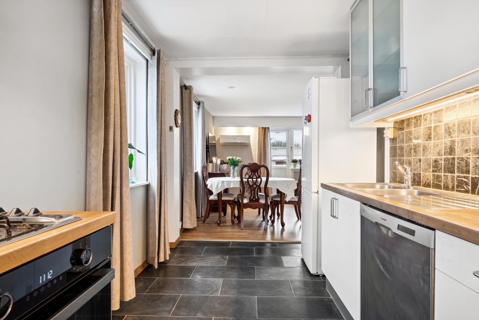 Flott kjøkken med Ikea kjøkkeninnredning, benkeplate av tre og integrert stekeovn og platetopp. Galleribilde