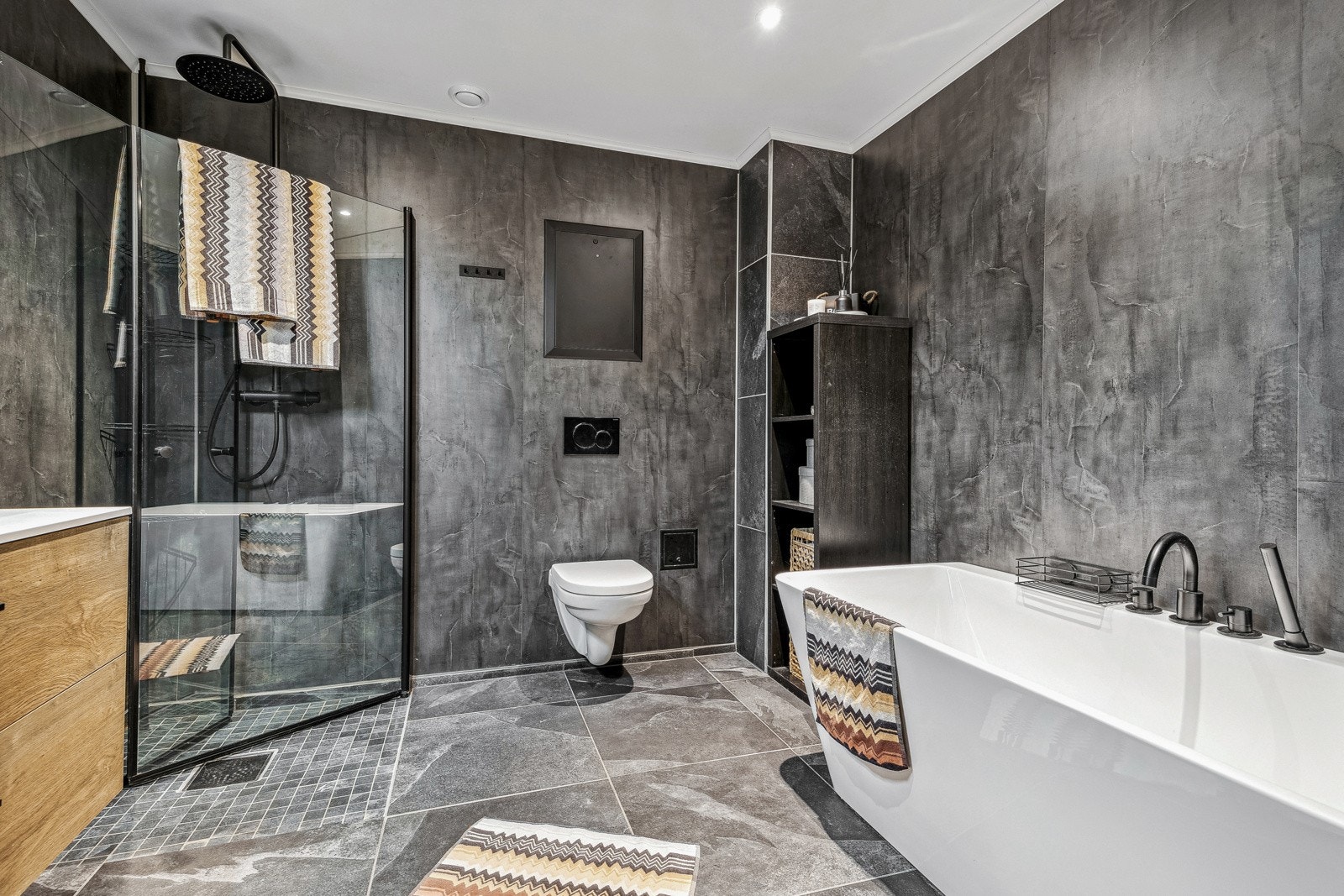 Opplev hverdagsluksus på badet, som er utstyrt med et dusjhjørne med dører, vegghengt dusjarmatur med regn- og hånddusj, samt et innbydende badekar. Galleribilde