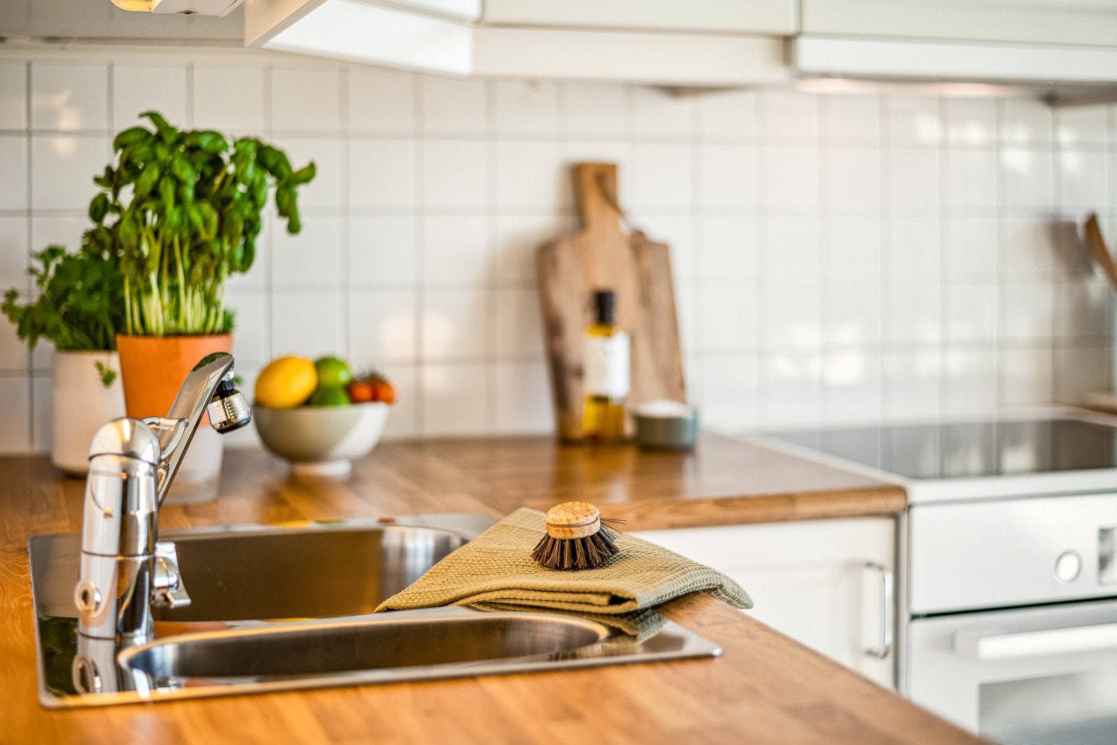 Kjøkkenet ar av klassisk stil med hvite, profilerte fronter og fliser mellom overskap og benkeplate. Galleribilde