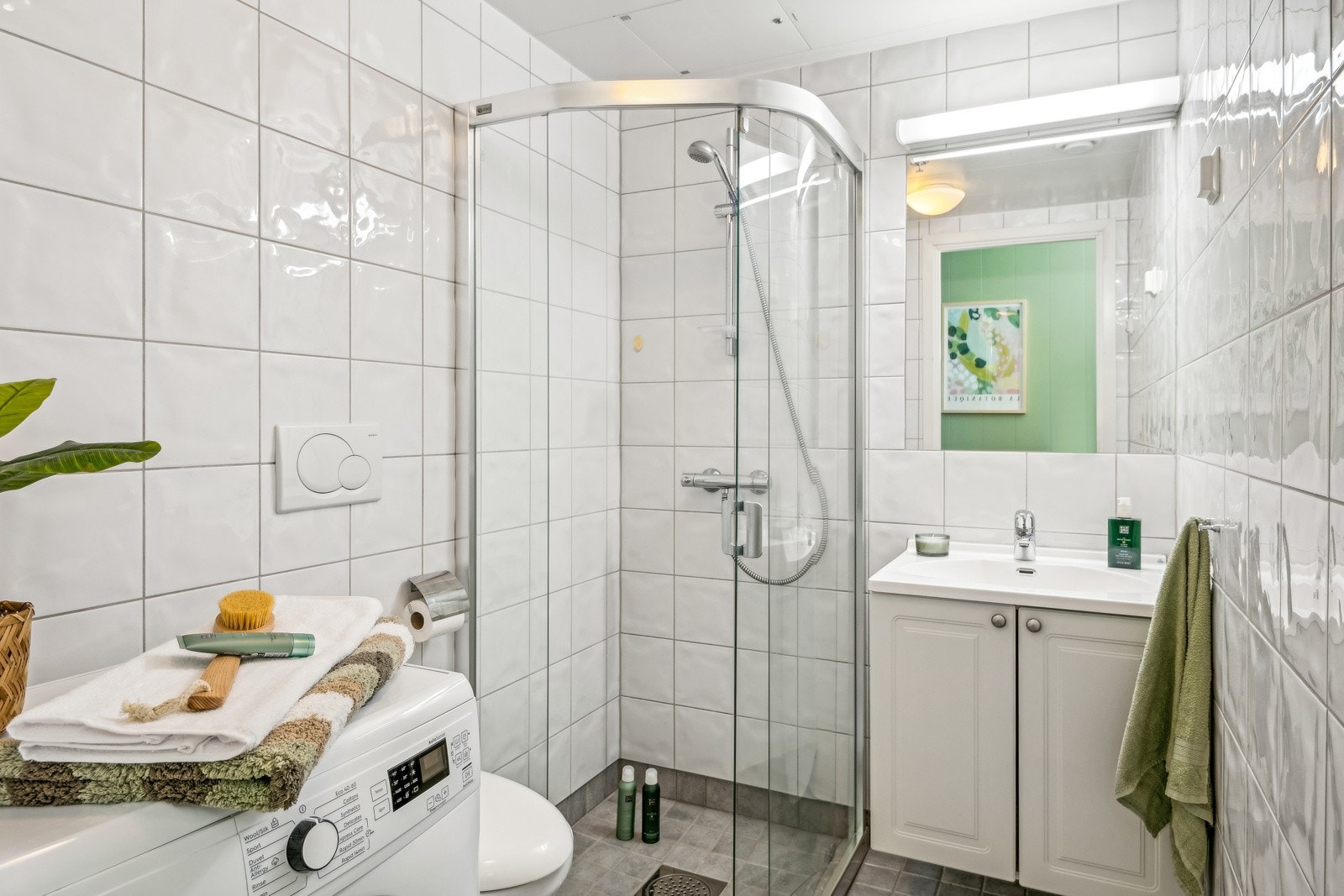 Baderommet er utstyrt med dusjhjørne, vegghengt servant og opplegg for vaskemaskin. Galleribilde