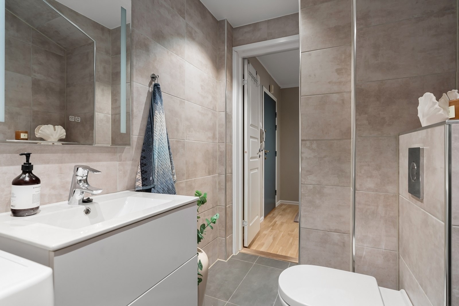 badet har også opplegg for vaskemaskin, servant med innredning, speilskap og vegghengt toalett Galleribilde