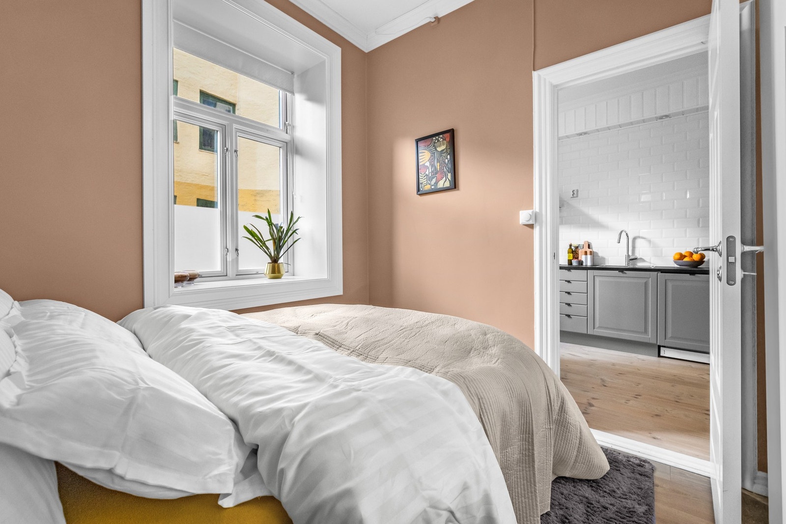 Soverommet har vegger malt i en dempet terrakottafarge fra 2021, gulv i laminat, bredt, hvitmalt listverk og plass til dobbeltseng. Galleribilde