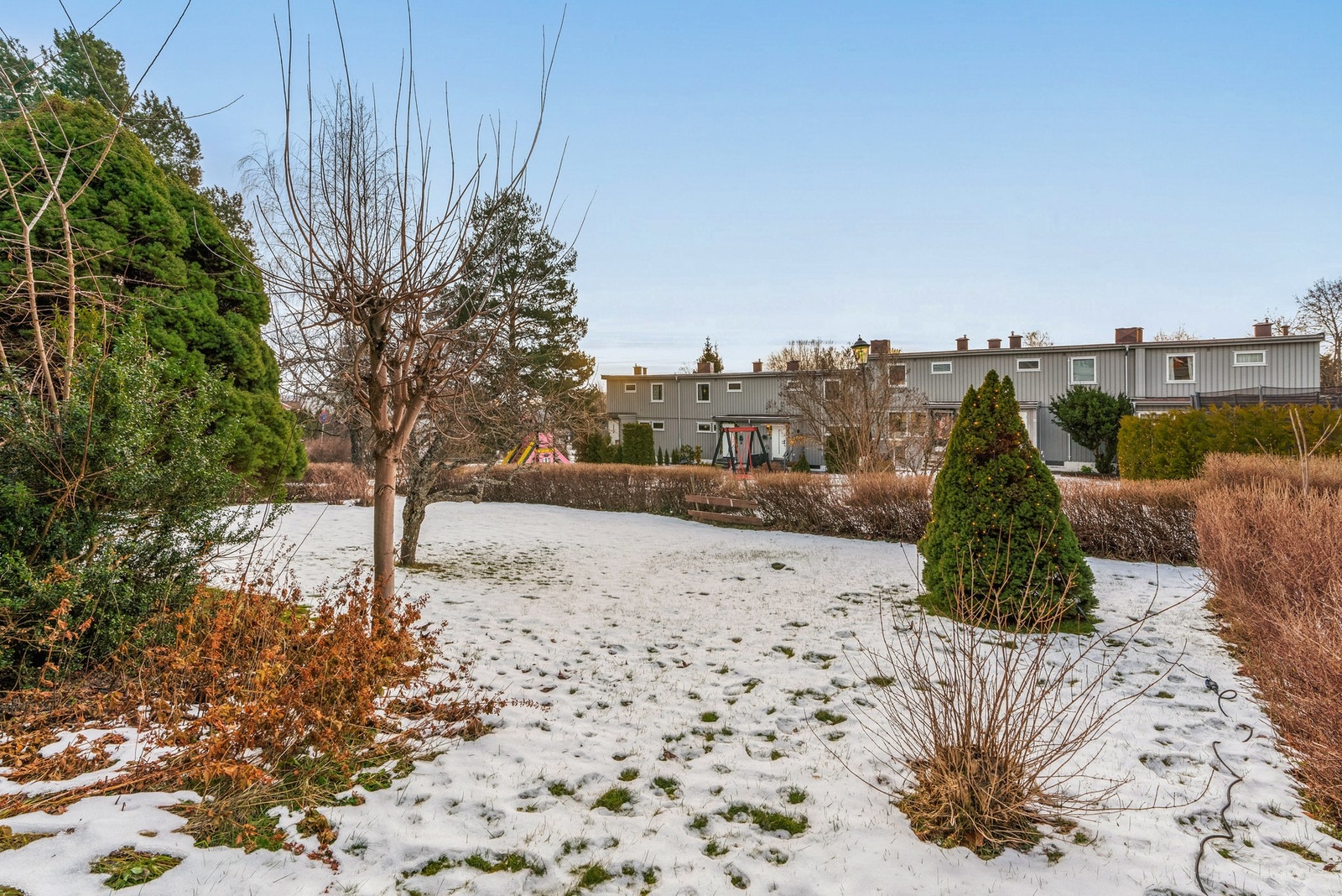Boligen disponerer hagearealet som ligger rett ut for den. Det er holdt åpent mot den ene naboen og beplantet med hekk mot den andre siden. Galleribilde