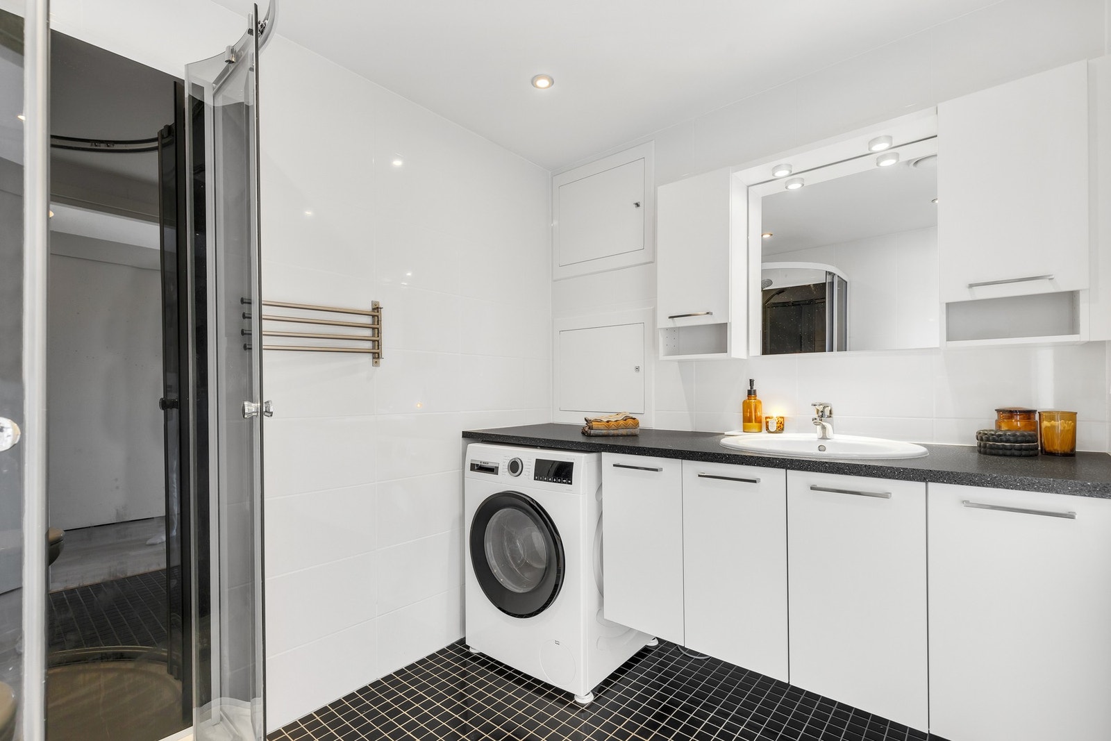 Flott flislagt bad med opplegg for vaskemaskin, vegghengt WC, servant med tilhørende baderomsinnredning. Galleribilde