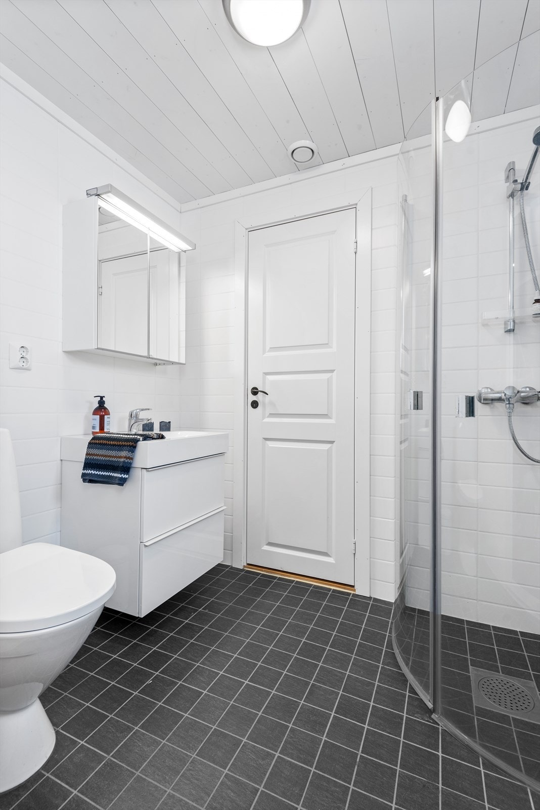 Begge badene har et moderne flisvalg på gulv og vegger og det er varmekabler i gulvet. Innenfor dette badet er det teknisk rom med varmtvannsbereder og lagringsplass. Rommet fungerer utmerket til tørking av klær. Galleribilde