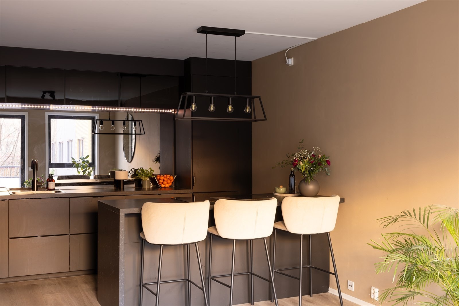 Lekkert kjøkken med mørke fronter og speil over kjøkkenbenk Galleribilde