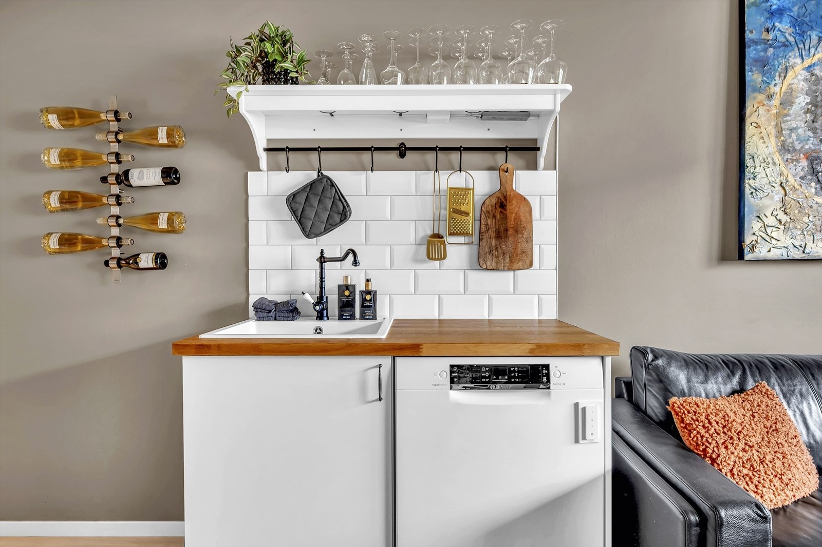 Lys innredning med glatte fronter, fliser på vegg over kjøkkenbenk og heltre benkeplate. Galleribilde