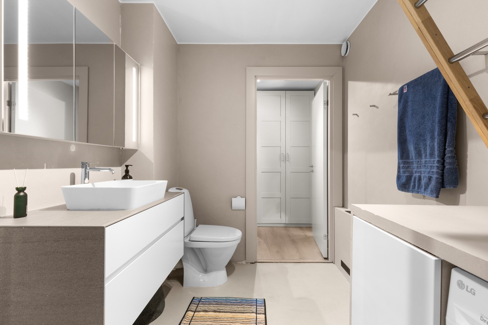 Baderommet inneholder servant med underskap, speil med belysning og stikkontakt, toalett og dusjhjørne med innfellbare glassdører og regndusj og hånddusj. Galleribilde