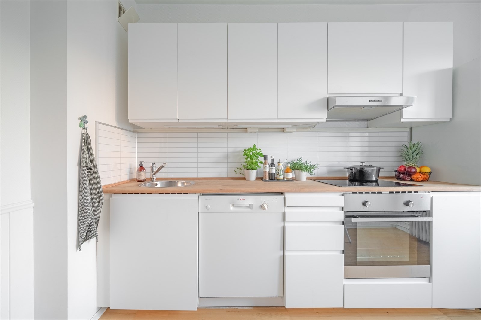 Kjøkkenet har hvite glatte fronter, heltre benkeplate og gode oppbevaringsmuligheter Galleribilde