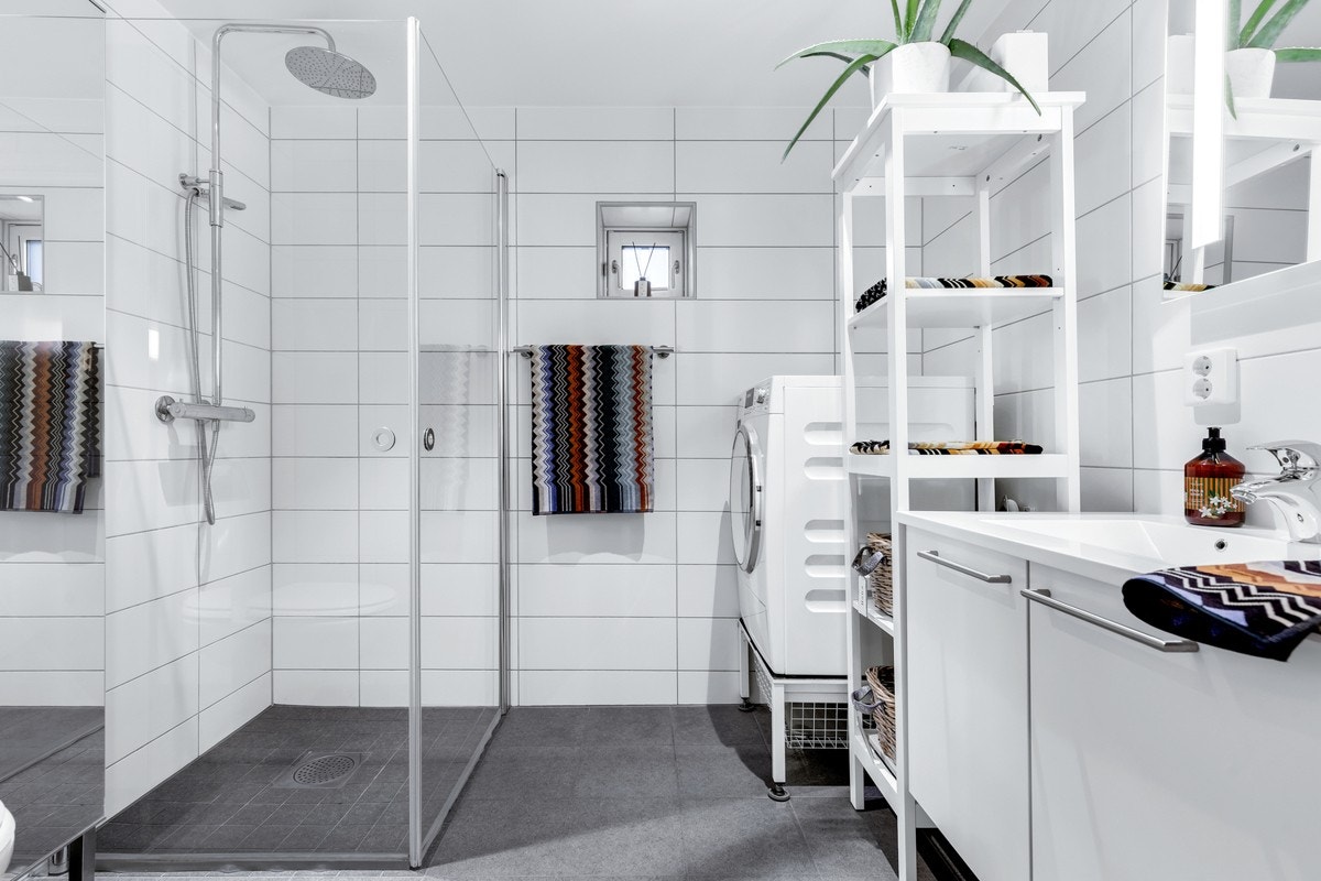 Baderom utstyrt med toalett, dusj med glassdører, opplegg for vaskemaskin, samt stilrent servantinnredning med speil. Galleribilde