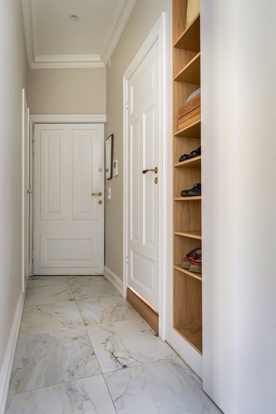 Entréen har store, delikate fliser på gulv med gulvvarme. Det er plass til oppbevaring av sko og yttertøy i plassbygd garderobeskap og hyller i nisje Galleribilde