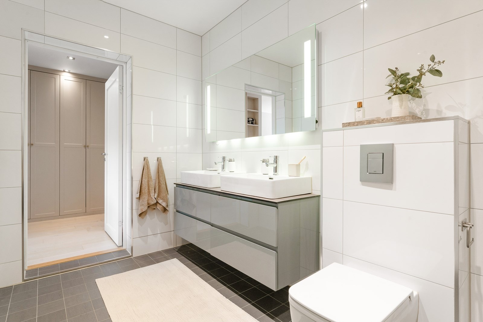 Flislagte gulv med gulvvarme, flislagte vegger og nedforet malt himling med integrert belysning. Galleribilde