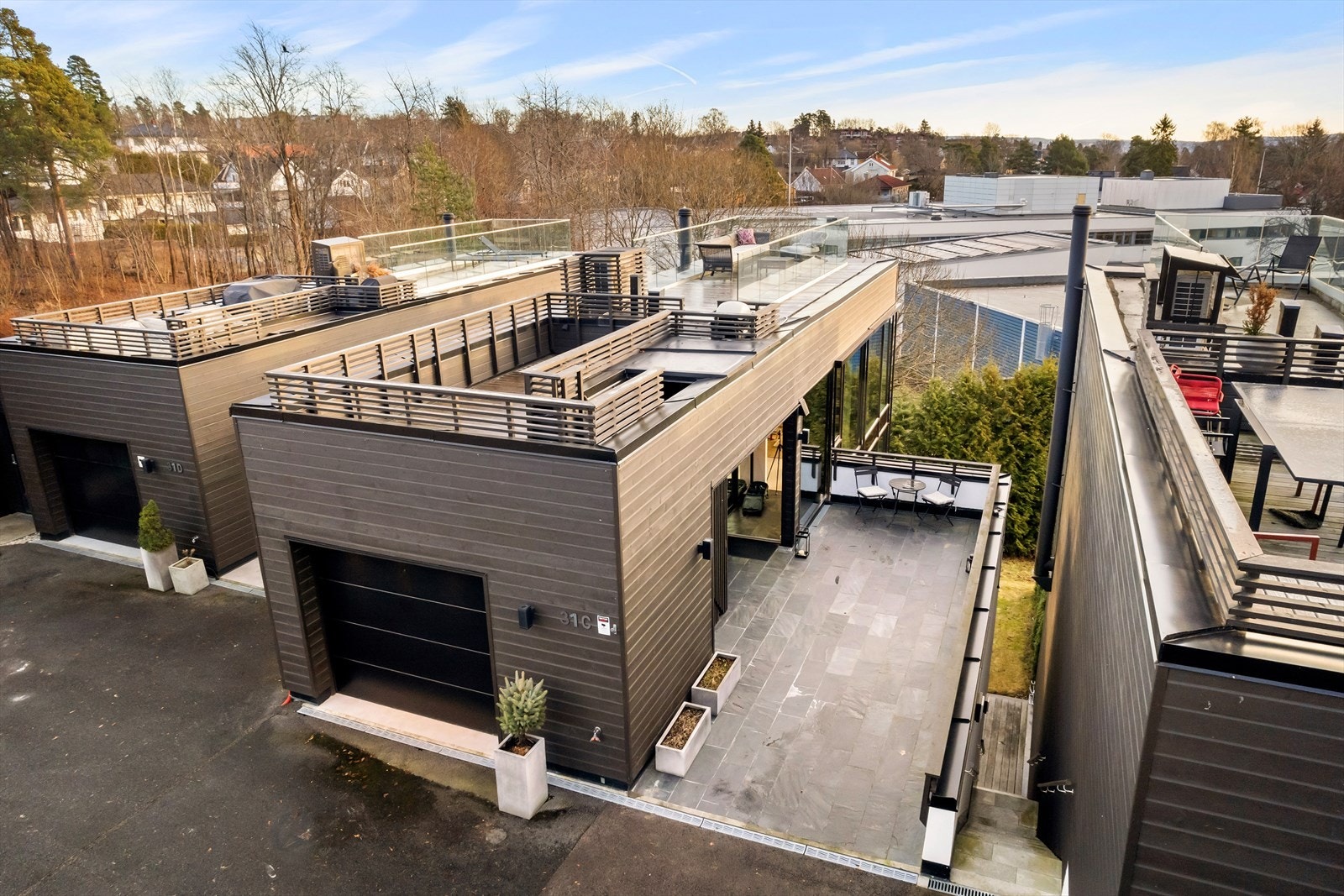 Romslig uteplass i forbindelse med inngangspartiet samt inngang til garasjen og trapp ned til hage/hybel. Galleribilde