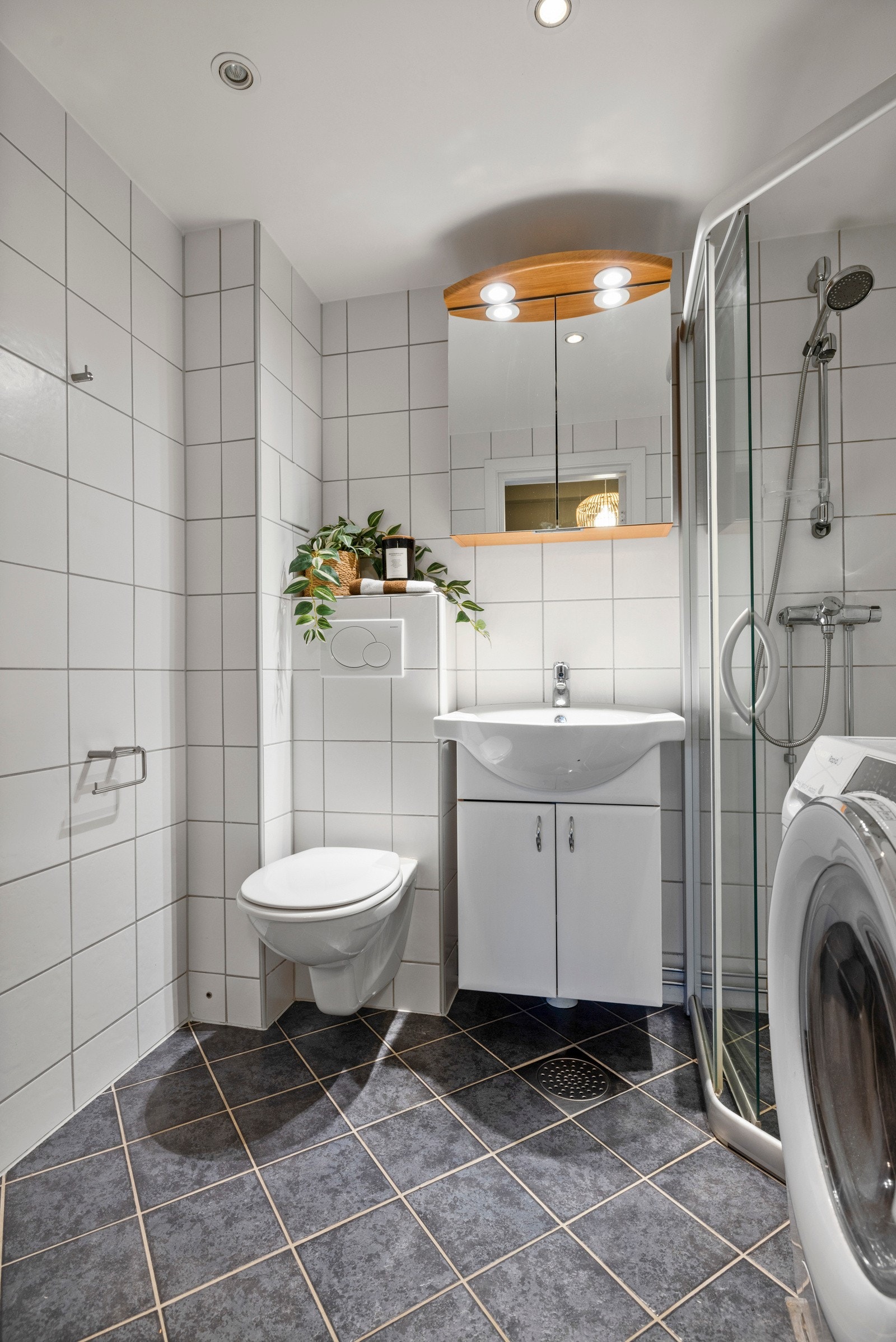 Her er det hvite fliser på veggene, downlights i himlingen og grå fliser på gulv med gulvvarme Galleribilde