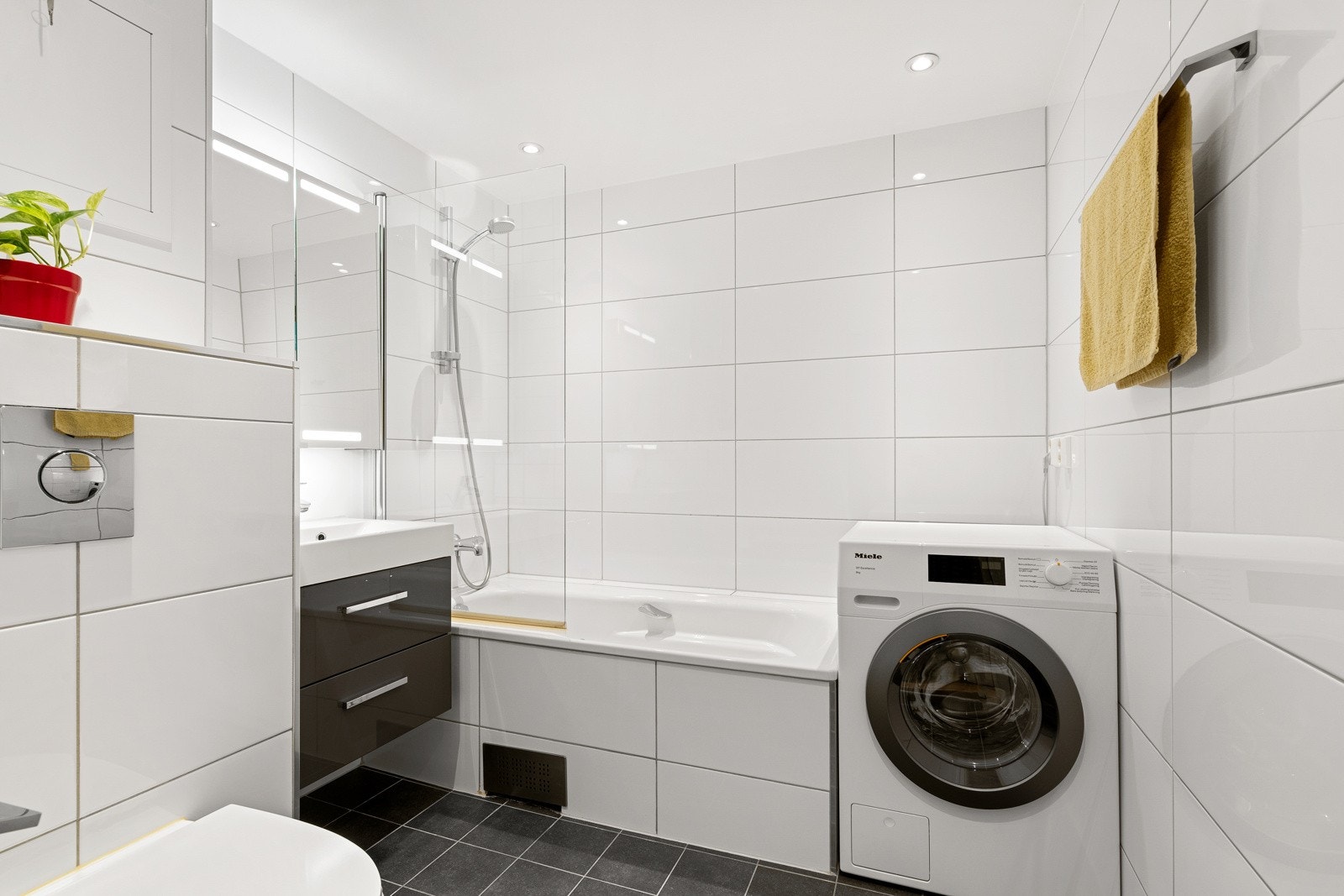 Flislagt og innbydende bad med varme i gulv og opplegg for vaskemaskin/tørketrommel. Galleribilde