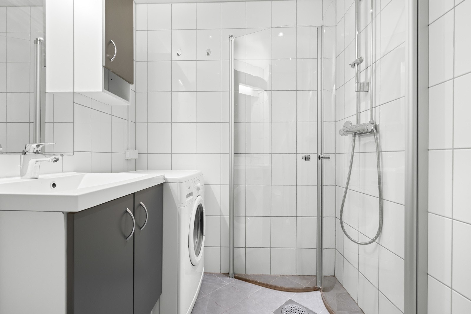 Badet er utstyrt med servant, vegghengt toalett, dusj rett på flis og opplegg for vaskemaskin. Galleribilde