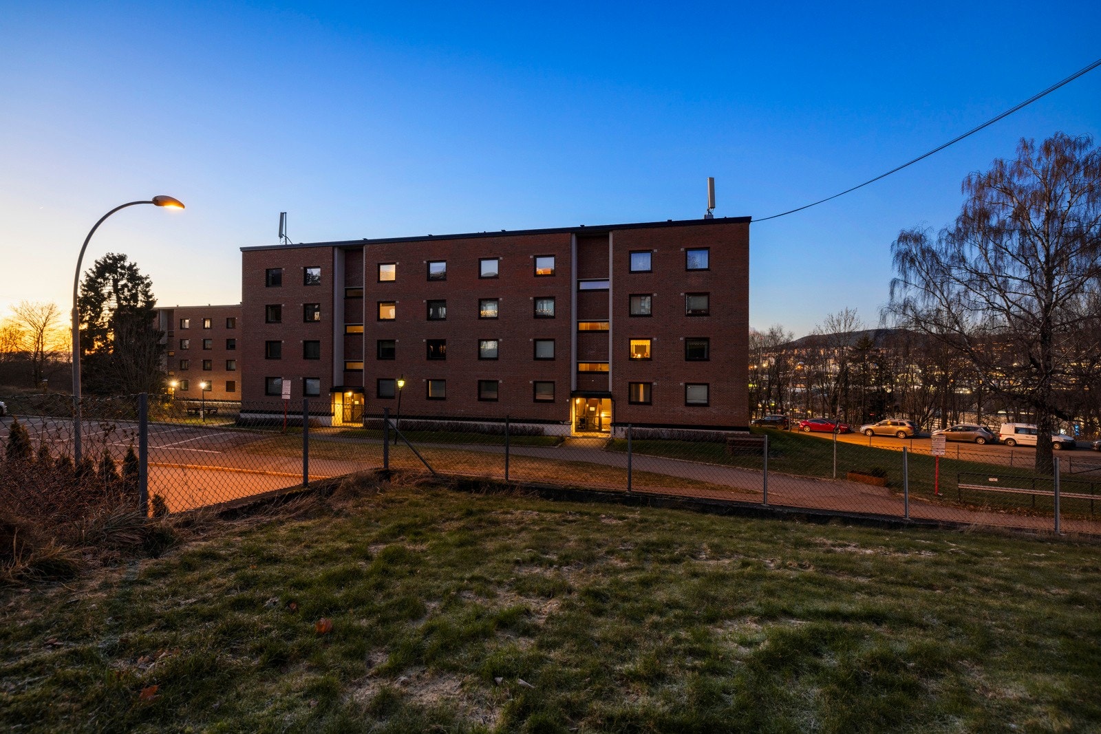 Rundt bygget er det en inngjerdet fellestomt med sykkelparkering, sittegrupper og lekeapparater Galleribilde