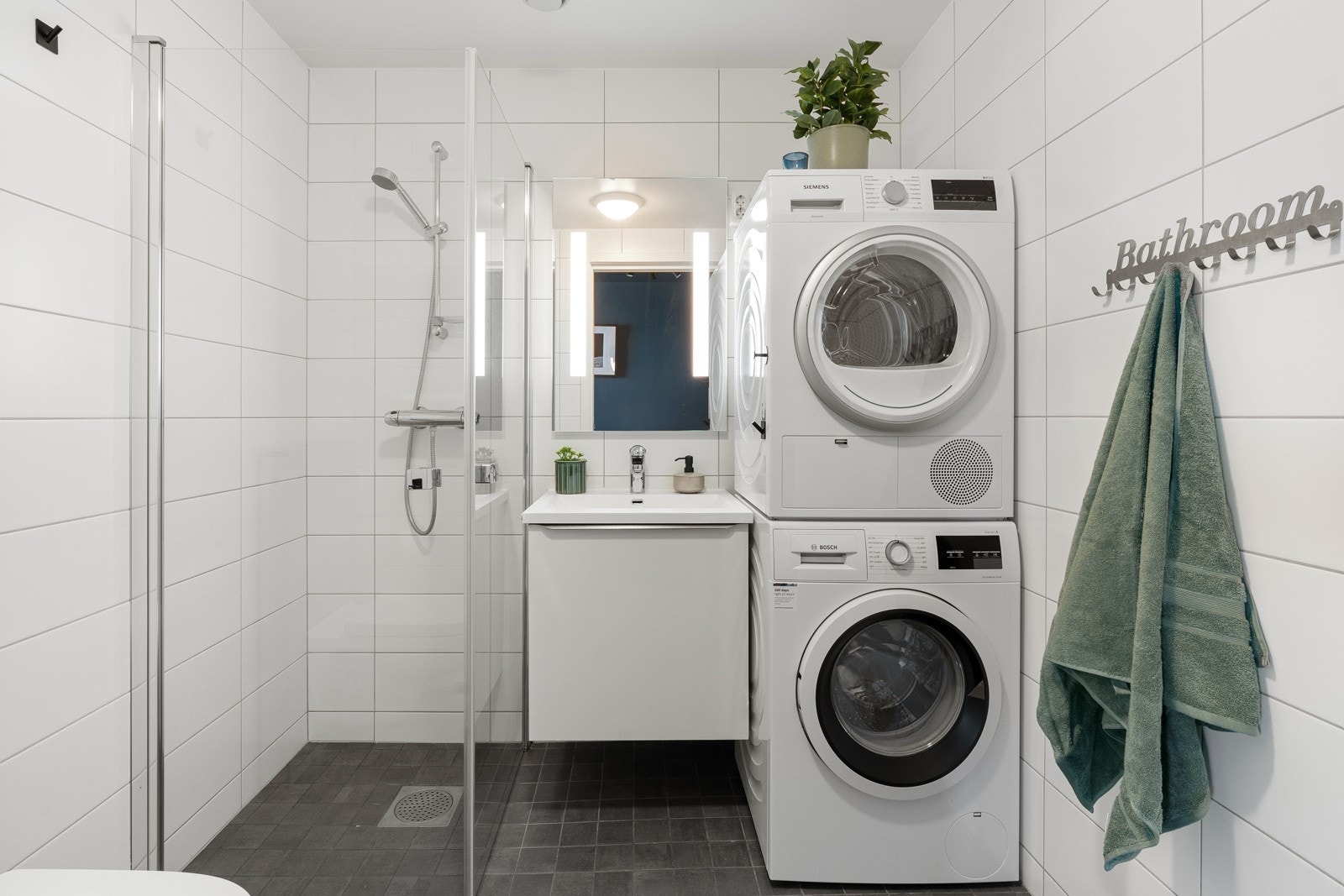 Lekkert flislagt bad med opplegg til vaskemaskin og tørketrommel. Galleribilde