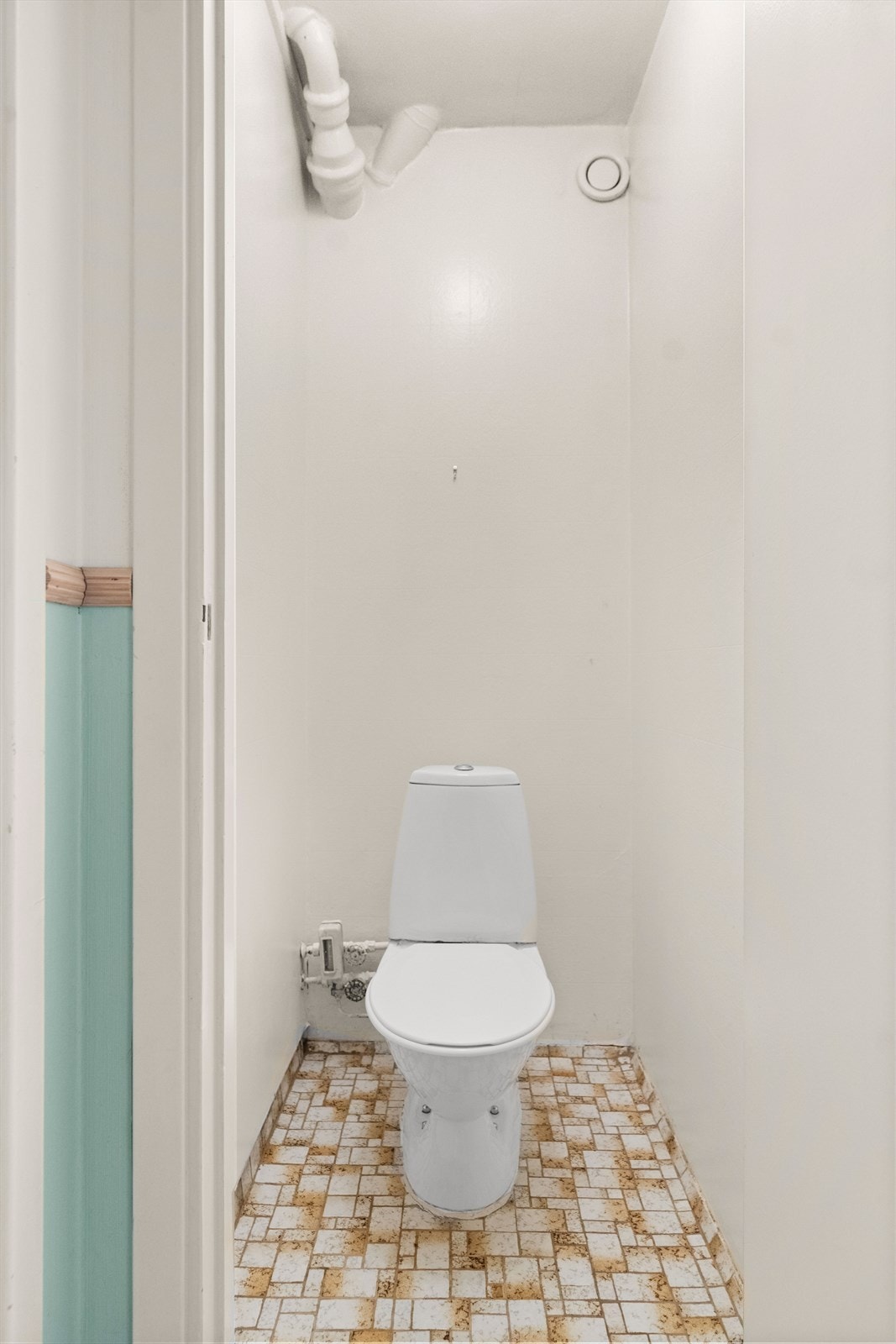 Vegg i vegg med badet ligger et separat toalettrom. Rommet har fliser på gulvet, tapet på veggene og betong i himlingen. Det er satt inn gulvmontert wc. Standarden er eldre, og renovering må påregnes. Galleribilde