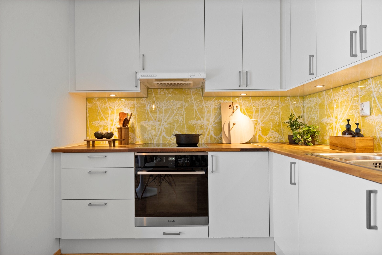 Kjøkkeninnredning fra Norema med heltre benkeplate, glassplate over benk, ventilator vifte og nedfelt kum. Galleribilde