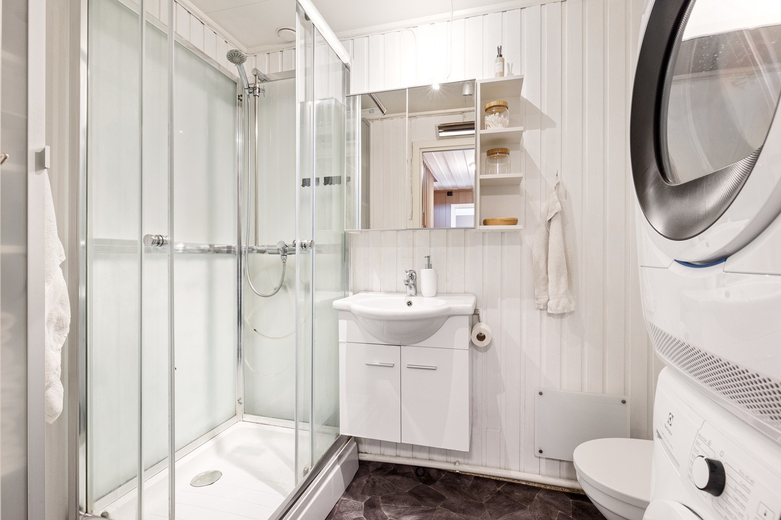 Baderommet er bestående av servant med underskap, dusjkabinett, toalett, opplegg for vaskemaskin og tørketrommel Galleribilde