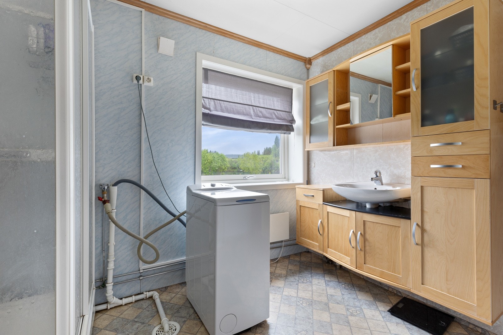 Baderom av god størrelse med opplegg for vaskemaskin, servant med underskap og dusjkabinett Galleribilde